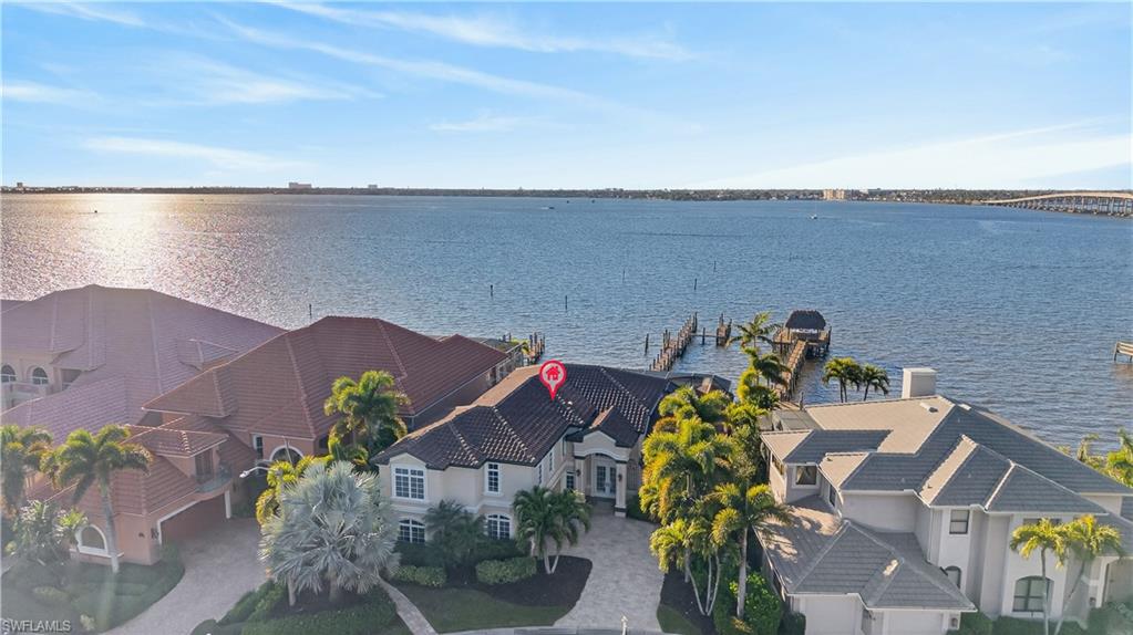 DIRECT RIVERFRONT ESTATE with breathtaking Caloosahatchee River sunsets, TWO BOAT SPACES INCLUDING A 50-FOOT MARINA SLIP, desirable X500 FLOOD ZONE DESIGNATION, and OPTIONAL CLUB MEMBERSHIP! Unlike most riverfront estates that sacrifice community amenities for privacy, 12782 Yacht Club Circle offers the best of both worlds! Located in Riverside Estates, an exclusive enclave within The Landings, residents enjoy gated security and the freedom to choose optional full or social club membership, offering golf, tennis, two restaurants, and a vibrant social calendar. Engineered for resilience yet designed for elegance, this extraordinary residence features a double concrete seawall, reinforced concrete-core pillars and cross-ties supporting the screened enclosure, impact-rated windows and doors, a NEW ROOF (2022), and electric roll-down storm screens—all seamlessly integrated into its refined architecture. A 160-foot private pier accommodates vessels up to 36 feet long with a 10-foot beam, while the INCLUDED 50-FOOT WET SLIP at Riverside Marina welcomes larger yachts. Outdoor living is spectacular, with a heated pool and spa, covered outdoor kitchen, and a 20x8 open-air waterfront deck offering front-row views of fireworks and seasonal boat parades. A spacious sunroom with a fireplace and 9-foot sliding glass doors brings the river views indoors. Soaring 20-foot ceilings, illuminated coffers, intricate crown molding, custom cabinetry, and exquisite millwork showcase timeless craftsmanship, complemented by a grand staircase with ornamental wrought-iron balusters and solid-core doors with ornate hardware. The expansive first-floor primary suite has a dressing room, sitting area, two walk-in closets and a steam-unit in the shower. Three upstairs guest suites feature en suite baths and dual-sink vanities, and a second-floor morning kitchen and laundry area provide added independence for guests. An open loft and study opens through French doors to an oversized balcony overlooking the river. Downstairs, a dedicated office with a walk-in closet, Murphy bed, and adjoining bath doubles as a fifth bedroom, while the upstairs study also enjoys its own private bath. A remarkable combination of architectural grandeur, waterfront living, exceptional boating access, and resort-style amenities without mandatory club fees.