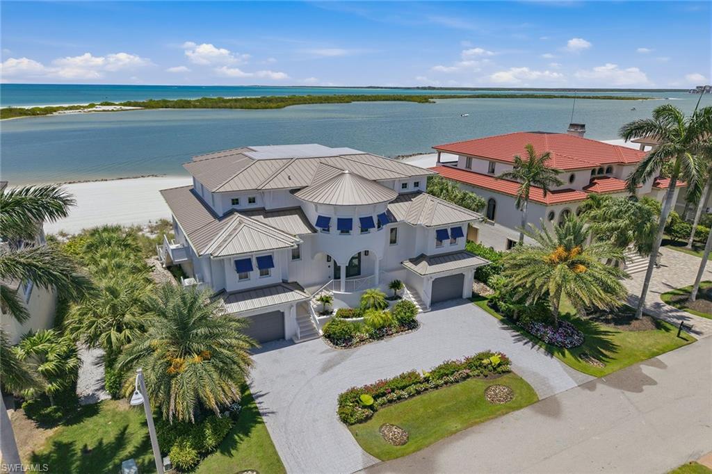 LIVE ON THE BEACH! A Jaw-dropping, extraordinary offering of rare distinction, this beachfront estate is gracefully positioned directly on the Gulf within the exclusive gated community of Hideaway Beach on Marco Island! With immediate beach access from your private residence, this remarkable home captures the essence of refined coastal living, where endless Gulf views, radiant sunsets and the soothing rhythm of the shoreline define everyday life. Completed in 2022, the residence reflects exceptional craftsmanship and forward-thinking design, seamlessly integrating the finest materials, modern technology and architectural elegance. Encompassing more than 5,500 square feet of refined living space, the home offers four luxurious bedroom suites, four full baths, one powder bath, a private media room and a spectacular Gulf-front primary suite designed as a serene coastal sanctuary Designed for grand entertaining and intimate living, the chef’s kitchen is appointed with premium appliances, an oversized quartz island with breakfast bar seating, an expansive butler’s pantry and a sophisticated wet bar with wine refrigeration. The adjoining dining area and great room are defined by soaring coffered ceilings, bespoke lighting, a dramatic fireplace, and full-height disappearing glass walls that open entirely to the beachfront lanai. With nearly 100 feet of direct Gulf frontage, the indoor and outdoor living spaces blend effortlessly against a backdrop of shimmering water and white sand beaches. The primary suite is a private retreat in every sense, offering sweeping Gulf views, a generous sitting area, spa-inspired bath, private water closet, and dedicated laundry area, creating a sanctuary of comfort and sophistication. A highlight of the residence is the private media room, designed as a cinematic experience with a built-in kitchenette, beverage cooler, sink and a state-of-the-art surround sound system. Seamlessly extending to the third-floor lanai, this space captures panoramic Gulf and beach views, an elevated setting for relaxation and sunset gatherings. Each guest suite is privately appointed with en-suite baths and direct balcony access, offering front-row views of iconic Marco Island sunsets and gentle Gulf breezes. The outdoor living experience is equally compelling. The Gulf-front pool lanai features a resort-style lap pool and multiple lounge areas, all oriented toward the beach for sunbathing, swimming and effortless access to the shoreline. Residents of Hideaway Beach enjoy an unmatched five-star lifestyle, including a private beachfront clubhouse with multiple dining venues and a resort-style community pool. It offers a newly completed state-of-the-art sports center, complemented by tennis, pickleball, bocce, golf and an exceptional array of amenities. This is more than a residence; it is a legacy beachfront estate offering a lifestyle of rare distinction in one of the Gulf’s prestigious communities!