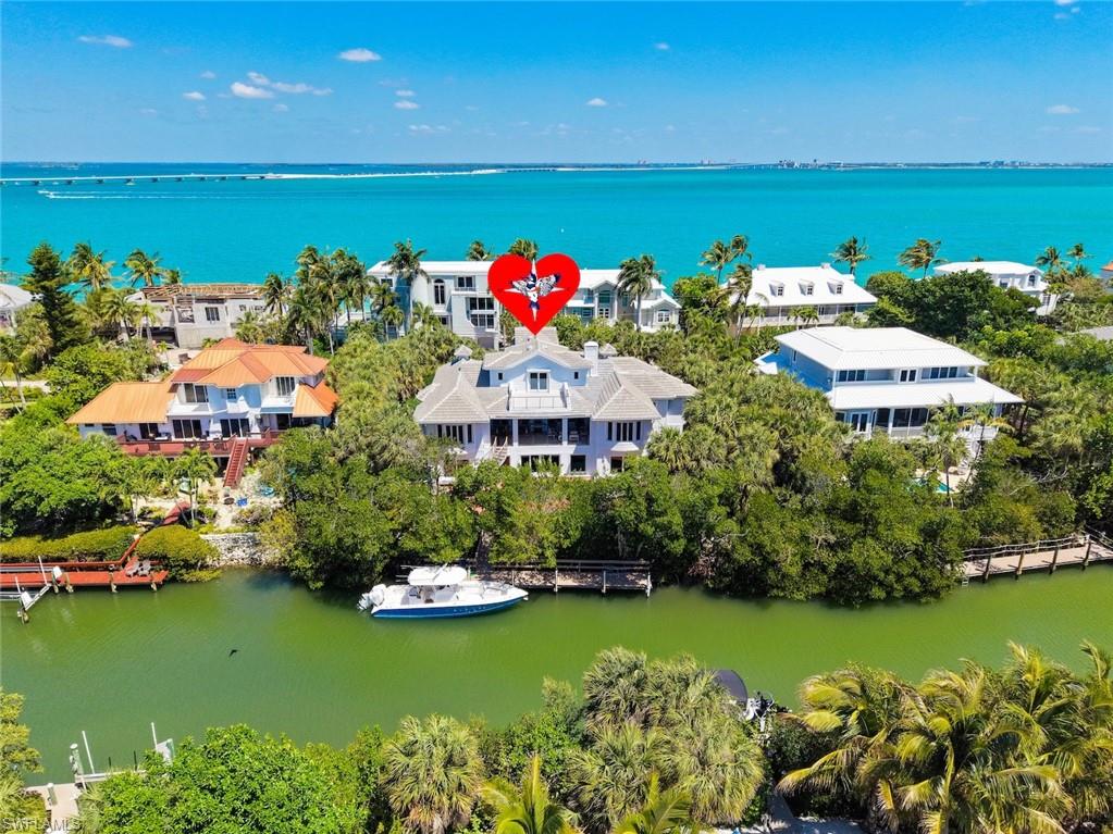 Situated along prestigious Lighthouse Way on the desirable East End, this exceptional coastal contemporary residence with116 ft of frontage affords deep water with quick direct Sailboat access to the calm bay waters and beyond. Complete with a private boat dockwith the potential to construct a boat lift (buyer to verify) and ideally positioned in close proximity to a full-service marina, waterfrontrestaurants, and island amenities, this home offers the ultimate boating lifestyle. Masterfully designed by Dwayne Bergman Interiors, thisresidence showcases a refined, sophisticated aesthetic paired with relaxed waterfront living and is superbly constructed of solid concrete onthe first two levels. Surrounded by turquoise water views and lush tropical landscaping, the setting is as impressive as the home itself. Inside, the light-filled open-concept living spaces feature hand-finished white oak flooring, and exceptional details including a striking glassstaircase that sets a modern architectural tone. The main living area flows seamlessly for both everyday living and entertaining, completewith a fireplace and custom wet bar. The designer kitchen is a true showpiece—sleek, bright, and highly functional featuring waterfall-edgeCambria countertops, an oversized island, custom cabinetry, premium appliances, and a spacious hidden pantry. With the kitchen openingdirectly to the dining and living areas it creates a cohesive and inviting gathering space. The primary suite is a private retreat with a spa-inspired bath and an expansive custom walk-in closet with built-ins. A dedicated home office or additional bedroom with balcony accessprovides a refined and flexible workspace. Outdoor living is equally exceptional. A large covered lanai with a tongue and groove pine ceilingand grilling area overlooks the heated saltwater pool and spa featuring vintage brick decking with copious space to relax and take in thecoastal surroundings. This residence presents a rare opportunity to own a meticulously designed waterfront home in one of the area's mostsought-after locations.