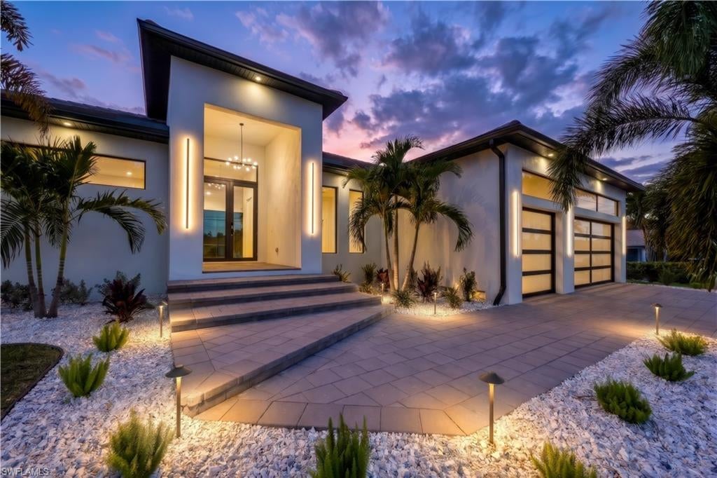 Experience the pinnacle of Southwest Florida waterfront living in this stunning, new construction home located on a Gulf access canal in beautiful SE Cape Coral. Showcasing sleek contemporary architecture and exceptional craftsmanship, this four-bedroom plus den, three-bathroom residence offers the perfect blend of luxury, comfort, and functionality. From the moment you arrive, the clean lines, modern façade, and spacious three-car garage set the tone for what awaits inside. Step through the impact-resistant double doors and into a bright, open-concept floor plan designed to maximize natural light and breathtaking canal views. Expansive impact-resistant windows and sliding glass doors seamlessly connect indoor and outdoor living spaces while providing peace of mind and energy efficiency. The heart of the home is the impressive modern kitchen, thoughtfully designed with both style and practicality in mind. Featuring sleek cabinetry, Thermador appliances, premium countertops, a large center island, a butler pantry with an additional LG refrigerator, and ample storage, this space is ideal for entertaining or everyday living. The kitchen flows effortlessly into the spacious living and dining areas, where a giant contemporary tiled fireplace creates a dramatic focal point and adds warmth and sophistication to the space. Tile flooring runs throughout the entire home, offering a cohesive look that is both elegant and easy to maintain. The luxurious primary suite is a private retreat with serene canal views, generous proportions, and a spacious walk-in closet. The spa-inspired primary bathroom features upscale finishes, dual vanities, and a beautifully appointed shower designed for relaxation. Three additional bedrooms provide comfort and flexibility for family and guests, while the dedicated den offers the perfect space for a home office, media room, or additional guest area. Step outside to your private waterfront oasis. The expansive screened lanai encloses a sparkling saltwater pool and heated Jacuzzi, creating the ultimate year-round retreat. Whether you are enjoying a morning swim, relaxing in the spa at sunset, or hosting weekend gatherings, this outdoor living space is designed to impress. The fully equipped outdoor barbecue area makes entertaining easy, while the picturesque canal view provides a tranquil and scenic backdrop; the canal itself provides bridge-free, near-immediate access to the open waters of the Gulf. With direct Gulf access, boating enthusiasts will appreciate the convenience and lifestyle that come with living on the water. This exceptional Gulf access property offers the very best of contemporary waterfront living in one of Florida’s most desirable coastal communities. Whether you are seeking a primary residence, seasonal retreat, or investment opportunity, this remarkable home delivers style, comfort, and the ultimate Florida lifestyle.