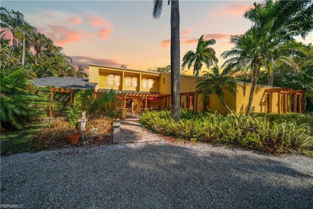 Discover a serene 1.7-acre retreat of lush, fully gated gardens and mature palm trees, perfectly private and secure. This remarkable estate features two residential buildings: a spacious main residence with 3 large bedrooms and 3 baths, plus a charming 2-bedroom, 2-bath bungalow guest house. A circular gravel driveway welcomes you to the property, complemented by a double carport and a separate aluminum shop/storage structure that may offer potential for additional garage space.

The main house is bright and impressive, featuring soaring 20-foot ceilings, high clerestory windows, an expansive family room, and plenty of room to add a pool—ideal for comfortable family living and entertaining. Step outside to a generous paved patio with a gazebo and wood-fired pizza oven, creating a wonderful setting for gatherings or simply enjoying the peaceful surroundings.

The property is surrounded by an impressive variety of mature fruit-producing trees and tropical plantings, including cocoplum, Japanese plum, mulberry, lychee, miracle berry, strawberry guava, acerola cherry, coffee, olive, banana, and several mango trees, adding beauty, privacy, and a unique garden-to-table lifestyle.

The bungalow is fully equipped for guests, extended family, or potential rental income, while a nearly finished tiny house provides additional flexible space for recreation, hobbies, or future use. Conveniently located with easy access to US-41 and I-75, this property offers a rare combination of tranquility, privacy, and accessibility. With multiple outdoor living areas, abundant mature landscaping, secure gated grounds, and exceptional versatility, this estate is ideal as a family compound, entertainer’s retreat, or income-producing opportunity.