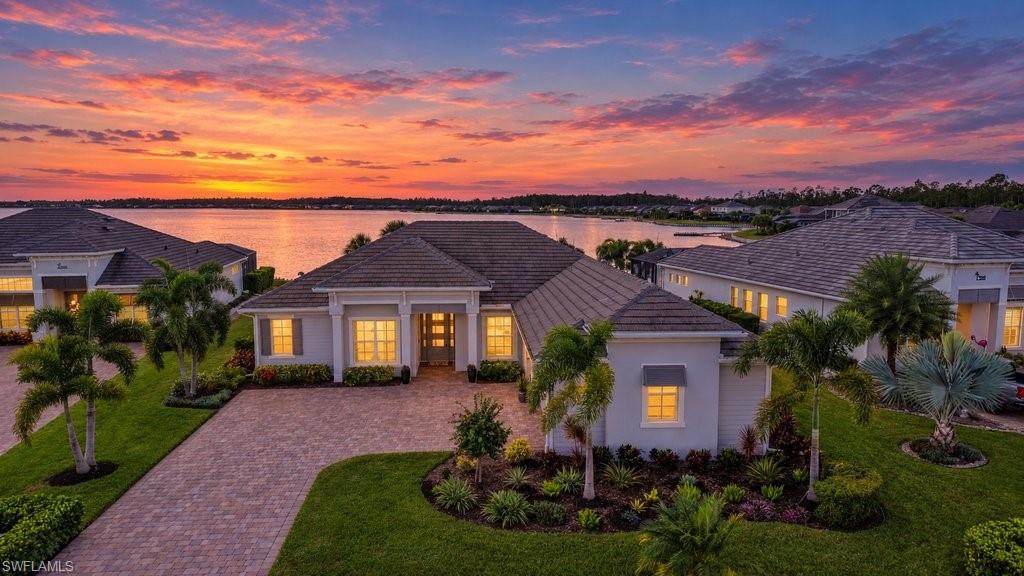 Situated on one of the community’s best lakefront locations in Vista at WildBlue! Enjoy all-day sunshine over the lake and pool, with spectacular Florida sunset views from this southwest, rear-facing home! This residence is a seamless blend of sophistication, comfort, and effortless resort-style living. Step inside and experience a thoughtfully curated open-concept design with a refined formal dining space, expansive great room and a chef-inspired kitchen, creating a welcoming space for gathering and entertaining. Sliding glass doors fill the home in natural light and open gracefully to the lanai, creating a seamless indoor-outdoor lifestyle. The gourmet kitchen features sleek quartz countertops, premium stainless-steel appliances, kitchen backsplash and a natural gas cooktop, perfectly suited for both casual and elevated dining experiences. The den offers versatile space for work and includes a custom Murphy bed, providing additional accommodation for your guests. Interior details include quartz countertops and tile floors throughout, designer light fixtures and ceiling fans, fresh interior paint, custom window treatments, new ceramic tile shower floors, and added trim around the windows, lanai doors, and bathroom mirrors. The lanai is designed to make every day feel like a getaway with a full-view screen enclosure that allows for panoramic lake views. Soak up the Florida sun in the sparkling upgraded pool and spa with the relaxing sounds of cascading waterfall bowls. Gather and entertain in the outdoor kitchen, set beneath a custom wood ceiling enhanced by Sono’s speakers, TV, ambient LED lanai lighting and electric storm shutters with access to a pool bathroom. Take a sip during cocktail hour while taking in sunsets on the custom floating dock which offers convenient access to the lake. The owner’s suite is a serene sanctuary, offering tranquil lake views and a spa-like ensuite, designed for ultimate relaxation. Two generously sized guest bedrooms offer a comfortable retreat for visitors. The laundry room provides extra cabinets for more storage space. Additional features include Impact window and doors, air-conditioned garage with insulated attic and garage doors, and epoxy garage floor. Outside, extensive landscaping is complemented by new sod and Foxtail palms added in 2026, landscape up-lighting and Bahama shutters. The HOA includes cable and internet, lawn care and irrigation for added ease of ownership. Residents of Vista at WildBlue enjoy an unparalleled lifestyle and amenities with an elegant lakefront clubhouse, indoor/outdoor dining, resort-style and lap pools, full-service spa, state-of-the-art fitness center, tennis and pickleball courts, bocce ball, boating, kayaking, and more. Perfectly positioned near several dining options, premier shopping, SW Florida International Airport, and the pristine beaches of Bonita Springs and Naples