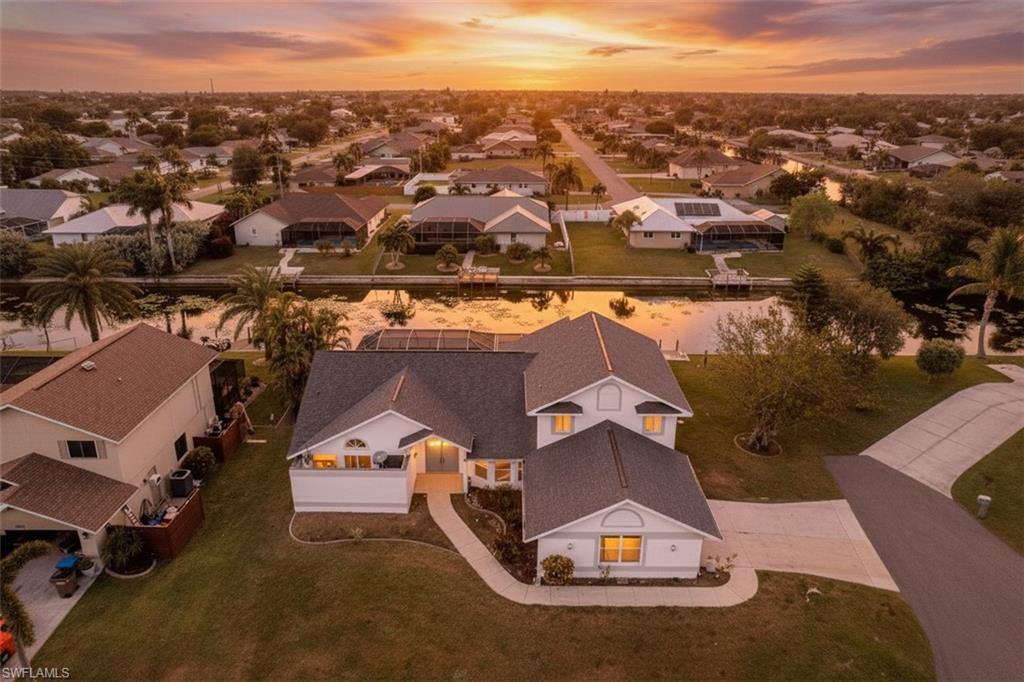 Waterfront Home with Oversized cul-de-sac Lot in Shamrock Lakes! Located at the end of a quiet street in the desirable Shamrock Lakes neighborhood, this spacious waterfront home sits on an oversized, hammerhead-shaped lot, offering 120 feet of waterfront, whereas most nearby lots offer only 80 feet. With 2,956 square feet of living space and nearly 5,000 total square feet, this home offers room for everyone with 5 bedrooms and 3 full bathrooms, perfect for large families, multi-generational living, vacation rental, or flexible options such as a home office or fitness room. The home features a new roof, a fresh coat of exterior and interior paint, and incredible potential for the next owner to customize to their taste. All upstairs windows are hurricane impact. Inside, natural light fills every room, and multiple sets of triple sliding glass doors bring expansive views of the pool and water into the living spaces. The open kitchen offers abundant natural light and overlooks the dining and pool areas, creating the ideal layout for entertaining. A separate living room and family room. The Master Suite is extremely spacious and features cathedral ceilings, wood flooring, and peaceful water views. The master bathroom includes dual sinks, a walk-in shower, a jetted soaking tub, and a private atrium that brings in natural light. Guest bedrooms are generously sized, offering comfort for visiting family and friends. Live the Florida lifestyle in the expansive screened pool area with large, covered spaces for dining and relaxing by the water. A concrete dock and seawall offer additional outdoor living space, perfect for fishing, lounging, or launching a kayak or paddleboard. This freshwater canal system connects to miles of lakes and waterways for boating, fishing, kayaking, paddleboarding, jet skiing, and more. Ideally located near Hunters Run Executive Golf Course, Sun Splash Family Waterpark, and Cape Coral’s premier dining and shopping, this home is also close to major redevelopment projects including The Cove at 47th, Bimini Square, the reimagined Cape Coral Yacht Club, and Slipaway Marina, all bringing vibrant new life, waterfront dining, entertainment, and community amenities to the area. Come experience the beauty and serenity of waterfront living on Shamrock Lakes, where every sunset and breeze reminds you why Southwest Florida is paradise.