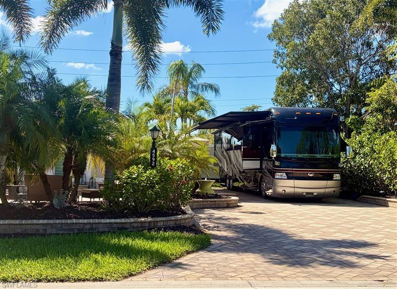 Class A motorcoach, off-lake site with northern exposure located in Pelican Lake Motorcoach Resort in Naples, FL. This property is upgraded with pattern pavers with a large expanded patio area including raised wall edging finishing off the sleek look.  The patio area is a serene oasis for relaxation with lush tropical landscaping surrounding the pad creating privacy and beauty. The coach house built on this property opens up to the patio with double French doors.  This site is move-in ready now and newly approved screen room would be a great addition as well. Custom built 308 square foot coach house in 2015 is finished with a full bathroom with stand alone shower, kitchen with wall oven and microwave, dishwasher, under counter wine fridge, small refrigerator, and stainless farmhouse kitchen sink, and large open living area with built in cabinetry. Furniture not included.