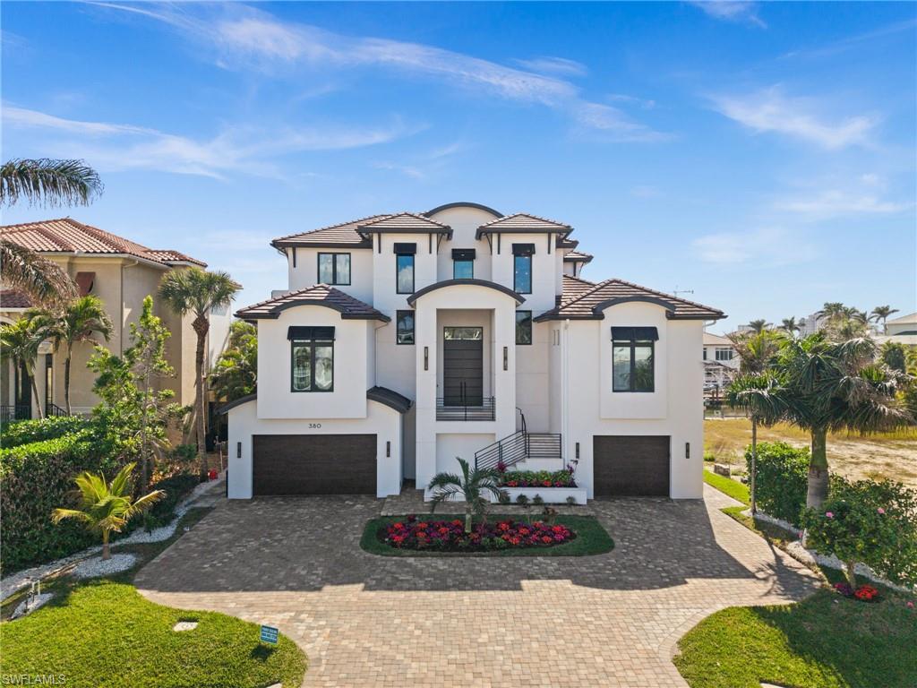 SOME HOMES ARE BEAUTIFUL. OTHERS ARE UNFORGETTABLE. At 380 Trade Winds Ave, waterfront living becomes an art form. Here, contemporary architecture meets the ever-changing beauty of the water, creating a residence where exceptional design and an extraordinary coastal setting exist in perfect harmony. Located in the prestigious Connors waterfront community, with the Gulf just minutes from your private dock, this is a home that doesn't simply offer the Naples lifestyle, it gives it an entirely new expression. Originally constructed in 2018 and subsequently transformed through an extraordinary renovation, this remarkable residence blends the advantages of newer construction with the sophistication of a meticulously reimagined modern estate. Offering 4,350 square feet of air-conditioned living space, 5 bedrooms, 6 full bathrooms, a private elevator, and an impressive eight-car garage, every detail reflects a commitment to exceptional living. The luxurious primary suite and three additional en-suite bedrooms provide beautifully appointed retreats, while the fifth bedroom, currently designed as an elegant office, enjoys access to a separate full bathroom. At the heart of the home, a spectacular designer kitchen with TWO expansive islands creates a stunning centerpiece for culinary experiences and memorable gatherings. Beautiful sliding glass doors frame the waterfront scenery, effortlessly connecting the sophisticated interiors with the outdoors. Rich hardwood flooring, custom closets, dramatic architectural accents, and a striking fireplace feature wall create an atmosphere of refined elegance. On the first level, an exquisite custom dry bar and adjoining wine room offer a distinctive setting for showcasing treasured vintages and entertaining in style.
A fully integrated Savant smart home system seamlessly controls lighting, climate, security, music, and entertainment, complemented by premium televisions and integrated speakers throughout the residence and outdoor living areas. The completely transformed pool and spa feature shimmering PebbleTec finishes, custom coping, integrated seating, and enchanting evening illumination. A professionally equipped Lynx outdoor kitchen, complemented by a second upper-level outdoor kitchen, create an exceptional atmosphere for entertaining and relaxation. Private dock access and a boat lift invite spontaneous Gulf adventures, while a whole-house generator, custom flood protection system, and sophisticated landscape lighting provide thoughtful convenience. Offered fully furnished with high-end interior and exterior furnishings, this residence delivers an effortless turnkey experience. Where Naples' celebrated coastline meets the privacy of waterfront living, 380 Trade Winds Ave holds a distinctive place in the luxury landscape. This is a rare convergence of architectural sophistication, waterfront privilege, and uncompromising design, created for those who appreciate the exceptional and settle for nothing less.