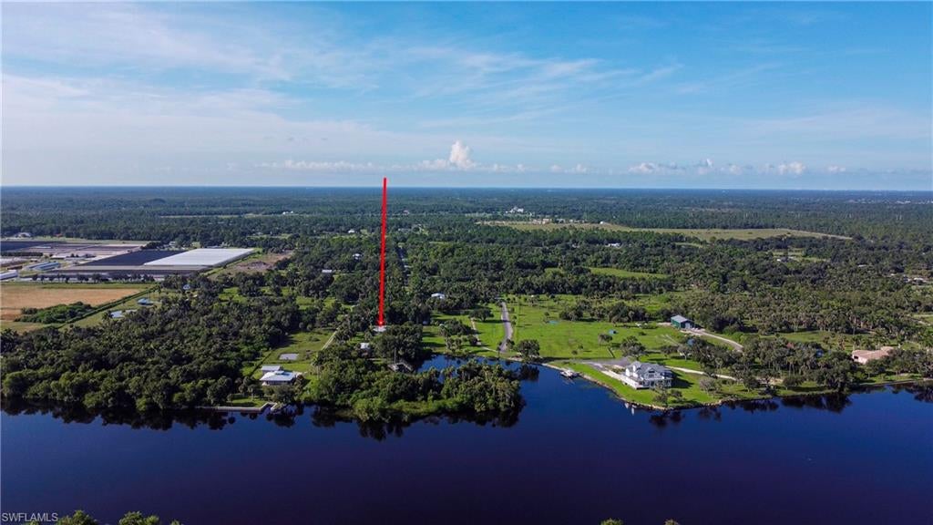 An amazing riverfront retreat: This 2.15 acre property offers a lot: a house, huge dock, detached 2nd garage/work area with living space, carport, pole barn, and trailer home. Situated on the Caloosahatchee river, enjoy boating and fishing from your backyard. Boat to the Gulf via the Franklin lock, or to the East coast through Lake O. Features: an open and sunny 1546 sq foot move-in ready home with river-views, 3 bedrooms, two baths, 2-car garage, Florida room, washer and dryer included. Concrete block construction, 2013 metal roof, new AC in 2023, new HWH in 2023. Plenty of yard space amongst the picturesque palms and live-oaks for a pool or playground. Then there is a wooden dock with 280+ linear feet of docking space in a protected calm cove. Water and electric at dock. Can easily tie up four 40 foot boats and one smaller boat, own your own flotilla or enjoy rental income by renting out dock space. Open 2-car carport, a detached garage/work area with a studio apartment, a pole barn that houses a 2 bedroom trailer. Plenty of room for guests, extended family, or for rental income. There is a pump house for the well equipment. Two septic systems. Lush tropical landscaping through-out, fire-pit, wood swing, mature avocado tree, coconut palms, and a gate at the entrance. The lot can even be divided into two one acre lots.