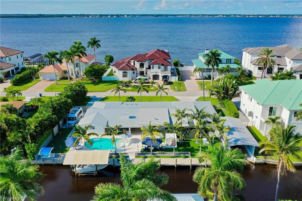 An extraordinary expression of Southwest Florida luxury waterfront living, 12743 Dennis Drive presents an exquisite fusion of sophisticated design, exceptional amenities and the ultimate boating lifestyle. Offering over 3,700 square feet, 4 bedrooms and 3.5 baths, this meticulously reimagined residence showcases interiors by Alexis Marie Interiors. The spectacular gourmet kitchen features quartzite countertops, an expansive gathering island, custom cabinetry, premium Miele appliances, a True refrigerator and dedicated coffee bar. Wood flooring, a striking glass-view fireplace and captivating water views complement the beautifully appointed interiors. The sumptuous primary suite features lanai access, a luxurious bath and custom dressing room. A truly distinguished waterfront amenity, the fully enclosed boathouse offers a level of boating accommodation seldom found in Southwest Florida, complemented by a boat lift and expansive composite docks. A climate-controlled wine cellar accommodates over 300 bottles with a sophisticated wine dispensing system. Designed for grand-scale entertaining, the outdoor sanctuary features a Viking-equipped summer kitchen, gas fireplace, heated saltwater pool, spa, illuminated putting green and spectacular sunsets. Additional appointments include RV storage with cleanout, outdoor shower, fish cleaning station, two-car garage, metal roof and impact-resistant windows and doors. Just minutes by boat to the Caloosahatchee River, with effortless access to Sanibel and waterfront dining. An unparalleled offering where refined luxury meets the quintessential Southwest Florida lifestyle.