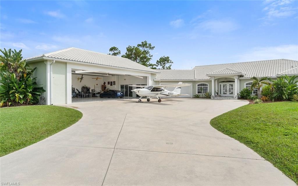 Welcome to Pine Shadow Air Park (94FL), where luxury living, aviation, and automotive passion come together in one extraordinary lakefront estate. Situated on over an acre, this custom property offers an unmatched lifestyle with direct taxiway access to the community's private, lighted 3,195+ foot asphalt runway featuring overrun and an on-site self-serve fueling station. The 3,187-square-foot residence is thoughtfully designed with 4 bedrooms, a den/office, 2 full baths, and 2 half baths. Soaring ceilings from 10 to 17 feet create an open, elegant atmosphere, while the spacious great room and living areas are perfect for entertaining or everyday living. At the center of the home, the chef's kitchen features granite countertops, stainless steel appliances, abundant cabinetry, and generous prep space. The luxurious primary suite serves as a private retreat with French doors opening directly to the lanai, dual vanities, a soaking tub, and a walk-in shower. Guest accommodations are equally well appointed with dual sinks and a walk-in shower, providing comfort and privacy for family and visitors. Designed with aviation enthusiasts and car collectors in mind, the property features an impressive 1,191-square-foot oversized 2+ car garage that seamlessly connects to a spectacular 2,700-square-foot climate-controlled aircraft hangar. The hangar offers a 42.5-foot-wide by 14-foot-high door opening, polished marble tile flooring, and sliding glass doors that transform the space into a showroom-quality environment for aircraft, exotic automobiles, RVs, or luxury collections. Outdoor living is truly resort-inspired. The expansive 5,719-square-foot screened lanai showcases a custom oversized heated saltwater pool complete with LED color-changing lighting, elegant water features, a sun shelf, and a spacious spa. Two rear patios overlook the tranquil lake, while an outdoor tile shower and dedicated pool bath add convenience for entertaining. As evening falls, the estate transforms into a breathtaking retreat with runway-inspired driveway lighting, architectural trim lighting, illuminated fountains, and a glowing pool that creates an unforgettable setting for relaxing or hosting guests while enjoying spectacular Southwest Florida sunsets over the lake. Beyond its luxury amenities, this home offers exceptional peace of mind. Elevated approximately 22 feet above sea level, the property has demonstrated outstanding resilience through recent hurricanes. It also represents tremendous value compared to building new, offering a completed luxury residence, resort-style pool, and premium aircraft hangar without the delays, uncertainty, and rising costs of new construction. This is more than a home, it's a lifestyle. A rare opportunity to own one of Pine Shadow Air Park's premier waterfront estates, where luxury, privacy, and the freedom of aviation come together. Come experience one of Southwest Florida's most remarkable aviation properties.