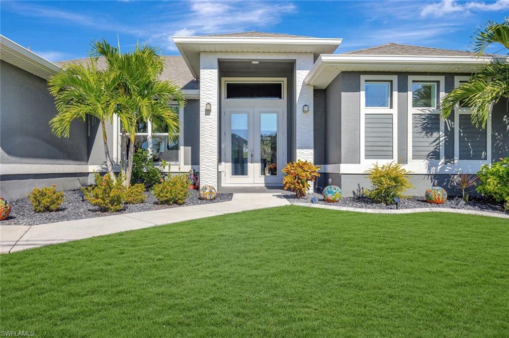 Where modern design meets true Florida relaxation—welcome to your next chapter. Experience everyday luxury in this 2021 contemporary pool home, where thoughtful design, natural light, and modern finishes come together to create a refined yet comfortable setting. Inside, the open-concept layout is framed by soaring tray ceilings, tall doorways, recessed lighting, and wide sliding glass doors that brighten each room. The kitchen blends style and function with a large island, stainless steel appliances with hood vent, a deep single-basin sink, dry bar, generous cabinet storage, and sleek stone counters—an ideal space for cooking or gathering with friends and family. The split-bedroom layout ensures privacy for everyone, with guest rooms featuring elegant tray ceilings and a stylish pool bath with floating cabinetry. The spacious primary suite feels like a personal retreat, offering two walk-in closets, a free-standing soaking tub, dual vanities with floating vanity cabinets, and an oversized fully tiled walk-in shower with dual shower heads. Step outside to a true Florida oasis—an electric-heated pool finished with shimmering glass tile, a screened enclosure, and a wide paver lanai that flows into a versatile outdoor deck designed for sunning, grilling, and entertaining, all framed by a lush Calusa hedge along the back for exceptional privacy. In the front, stone accents, palms, and lava rock landscaping set the tone for the home’s warm, tropical welcome. Additional highlights include impact-rated windows and doors, a welcoming front double-door entry, window shades, a dedicated laundry room, and a full three-car garage with excellent storage possibilities. Positioned on a beautifully landscaped corner lot in the thriving NW Cape Coral corridor, the home offers quick access to parks, schools, shopping, and growing development—bringing both convenience and long-term value. For added peace of mind, the property includes irrigation, an HVAC system serviced twice yearly, and a surge protector installed on the HVAC.