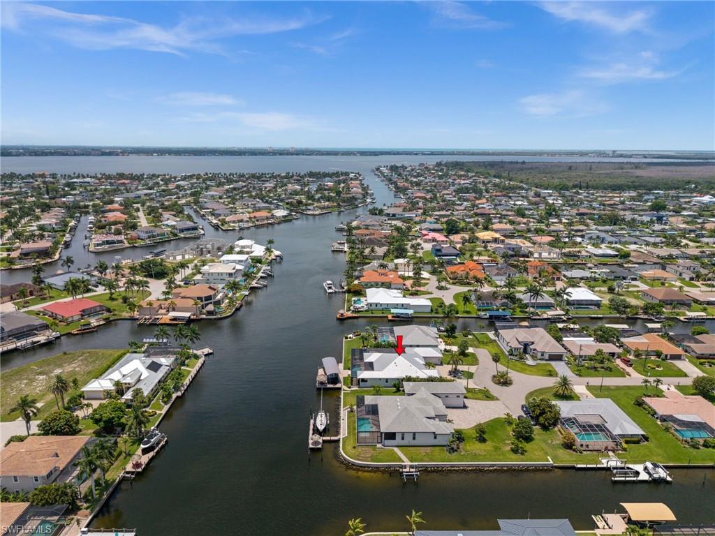 DIRECT SAILBOAT GULF ACCESS | 200-FOOT-WIDE SAN CARLOS CANAL | 95 FEET OF WATERFRONT | TRIPLE LOT | 5+ CAR GARAGE

This is the waterfront property boaters dream about! At the end of a cul-de-sac on a .31-acre TRIPLE LOT, this custom 4-bedroom + OFFICE + EXERCISE ROOM, 3.5-bath home offers DIRECT SAILBOAT GULF ACCESS, spectacular INTERSECTING CANAL BASIN VIEWS, and 95 FEET OF WATERFRONT on the 200-foot-wide San Carlos Canal. With 2,650 sq ft, a HEATED SALTWATER POOL & SPA, and an exceptional 5+ CAR GARAGE/WORKSHOP, this home was designed for the Southwest Florida lifestyle.

Boaters, car enthusiasts, collectors, and hobbyists will love the garage setup. The attached 2-car garage is complemented by a separate 3+ CAR GARAGE/MANCAVE with 11-foot ceilings, custom overhead storage, workshop space, and glass French doors opening to the lanai. Plenty of room for vehicles, a lift, boats, motorcycles, golf carts, hobbies, and all the toys that come with Florida living.

The exterior features a paver driveway, front porch, walkways, and expansive pool deck. Double entry doors with transom glass welcome you inside, where 10-FOOT CEILINGS, 8-FOOT DOORS, TILE FLOORING, TRAY CEILINGS, and designer details create an upscale yet comfortable feel. A dramatic stacked-stone feature wall with linear electric fireplace anchors the living area, while whole-home and lanai surround sound and ZERO-CORNER SLIDERS bring the waterfront views inside.

The chef’s kitchen features soft-close cabinetry, a HUGE CENTER ISLAND, WALK-IN PANTRY, COFFEE BAR, KitchenAid wall oven and microwave, 42-inch refrigerator, and SIX-BURNER GAS RANGE supplied by an on-site buried propane tank.
The spacious primary suite captures canal views and offers direct lanai access, double tray ceiling, two walk-in closets, dual sinks, and a custom-tiled glass shower. A junior suite, poolside bedroom, fourth bedroom with French doors, office nook, separate exercise room/office, and well-equipped laundry room complete the interior.
The expansive screened lanai features covered living and dining areas plus an OUTDOOR KITCHEN WITH PROPANE GRILL AND BAR SEATING. The HEATED SALTWATER POOL includes a tanning shelf and spa with waterfall, framed by dramatic picture-window screens overlooking the wide canal and intersecting basin.
The composite dock features a TIKI HUT, CAPTAIN’S WALK, SEATING AREA, and COVERED 30,000-LB BOAT LIFT WITH GEM REMOTE. Enjoy DIRECT SAILBOAT ACCESS and a quick trip to open water.
Additional features include IMPACT WINDOWS & DOORS, METAL ROOF, BAHAMA SHUTTERS, and a custom security/camera system.

The home sits DIRECTLY ON THE CHRISTMAS BOAT PARADE ROUTE, just minutes to open water and close to the brand-new Bimini Basin restaurants and shopping, Tarpon Point, Cape Harbour, and downtown Cape Coral.

Exceptional waterfront, incredible boating access, unmatched garage space, resort-style outdoor living. This is Southwest Florida waterfront living at its best.