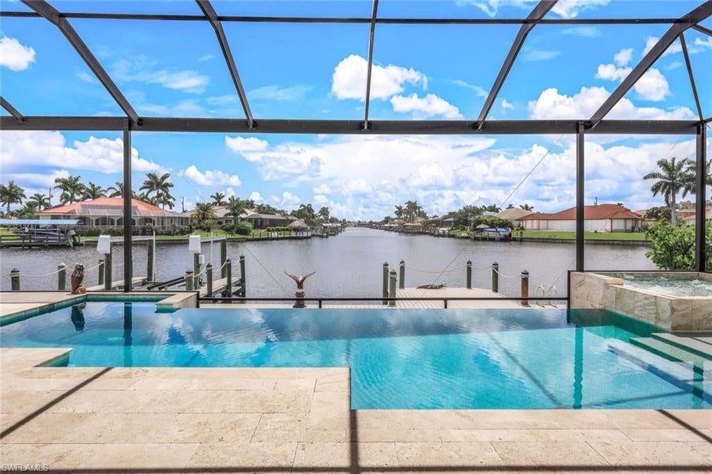 ONE OF A KIND WATERVIEW! Welcome to your dream waterfront oasis! This stunning, contemporary residence offers a truly luxurious living experience right in the heart of preferred Southwest Cape Coral. With access to the Gulf of Mexico, each morning promises breathtaking Floridian sunrises and unparalleled vistas stretching down a beautiful canal intersection. This home’s exquisite design features soaring high ceilings that complement the zero-corner sliding doors, seamlessly blending the indoor opulence with the natural beauty outdoors. The expansive living area opens directly to an oversized patio, hosting an electrically heated salt-water pool and spa adorned with a vanishing edge – perfect for those who appreciate the art of relaxation. Lush landscaping and large panorama screens offer unobstructed views, ensuring that you are never more than a glance away from serenity.The interior speaks volumes about luxury with its meticulously maintained travertine and tile flooring throughout. The grand primary bedroom serves as a sanctuary, equipped with separate his and hers walk-in closets. For boating enthusiasts, the composite boat dock features a captain’s walk, conveniently ushering you directly onto the water from your backyard. Additionally, the three-car garage sports classy Epoxy flooring, which means even your vehicles rest in style. Convenience is key, and living here means you're just moments away from the Cape Harbour Marina with its numerous shopping and dining options. Whether it's groceries from the nearby Publix Super Market at Camelot Isles Shopping Center, a leisurely walk at Camelot Park, or an evening at the Cape Harbour Marina, everything you need is within easy reach. This turnkey home is nothing short of spectacular, offering privacy, luxury, and convenience seamlessly crafted into one awe-inspiring package. It’s not just another beautiful property; it’s the lifestyle upgrade you deserve. Don't just chase dreams—live them in this exceptional Cape Coral haven!
