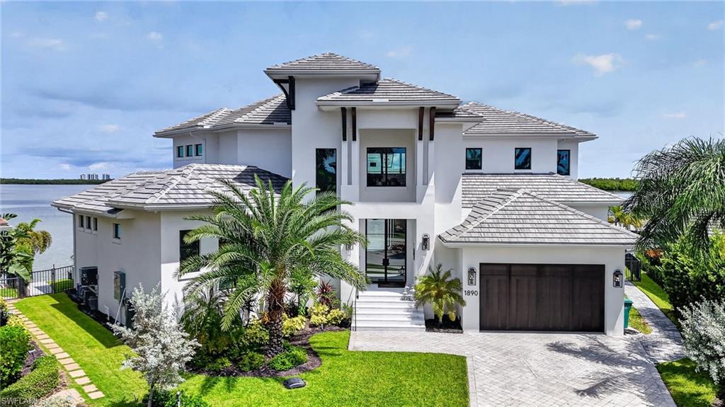 Experience the pinnacle of waterfront luxury in this newly constructed 2023 estate, offering 4,212 square feet under air and 5,894 square feet of total living space. From the moment you step through the front door, you are greeted by breathtaking, unobstructed wide-water views of Sanctuary Sound and the Gulf of America that set the tone for the entire residence. The home is built at 10 feet of elevation and wrapped in PGT impact windows and doors, with soaring 12-foot ceilings in the principal living spaces and a layout designed for both grand entertaining and refined coastal living.
At the heart of the home, the chef’s kitchen is impeccably appointed with custom maple and walnut cabinetry, a Sub-Zero refrigerator, and a propane Wolf range, complemented by a walk-in pantry. A floor-to-ceiling wine wall on a walnut backdrop anchors the dining room, with an undercounter wine cooler alongside. French oak flooring and a matching beamed ceiling flow through these rooms, giving the interior a cohesive, luxurious finish. An elevator connects both levels with ease.
The first-floor primary suite is a private retreat, featuring water views, a spa-inspired bath, and two generously sized walk-in closets. A ground-level study opens to the lanai and offers breathtaking views of the water—an elegant workspace set directly on the Sound.
Upstairs are three bedrooms and two full bathrooms, including a private suite with its own bath and direct access to the second-floor porch. A family room also opens onto that porch—perfect for enjoying sweeping, unobstructed views and coastal breezes.
Outdoor living is equally impressive, showcasing an infinity pool and spa set against the backdrop of open water. Nearly 780 square feet of first-floor lanai and a fully equipped outdoor kitchen create the ideal setting for effortless entertaining along the waterfront. With 160 feet of seawall, the property presents a true waterfront estate on Sanctuary Sound and the Gulf of America. A whole-home generator, 1,000-gallon propane tank, and reverse-osmosis water treatment system complete this exceptional island residence.
Minutes from shopping and dining by car, with waterfront restaurants just a ten-minute boat ride away.