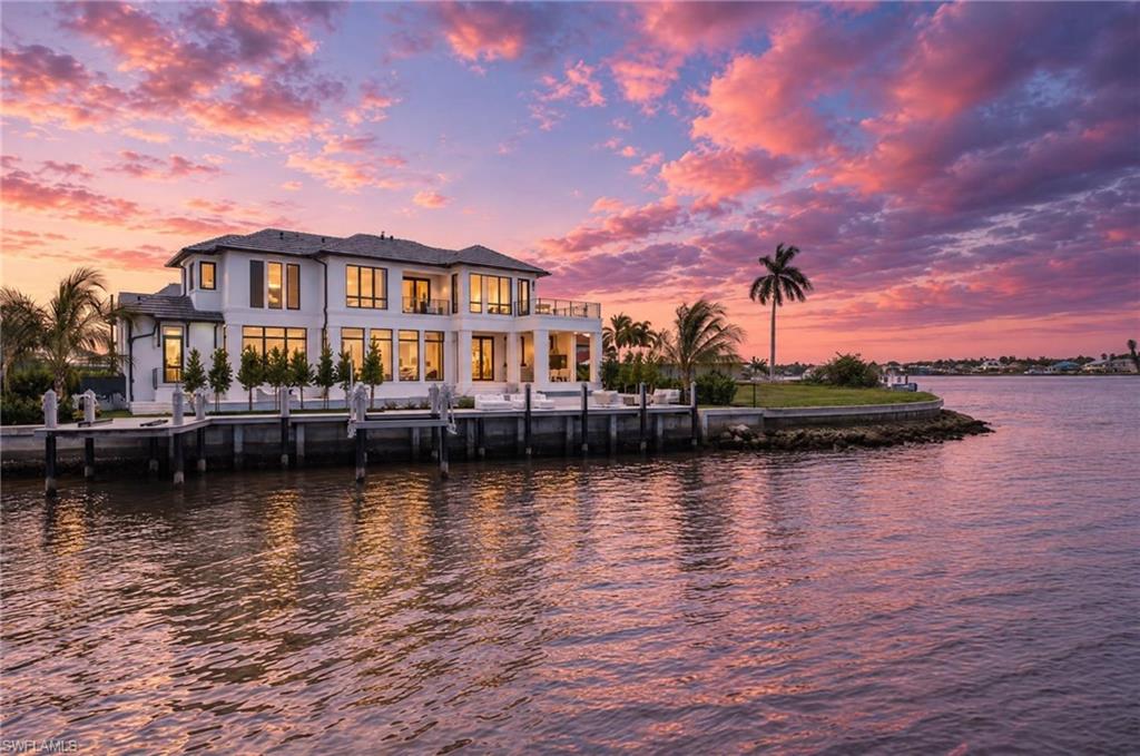 NEW CONSTRUCTION in coveted Naples Bay featuring 121 feet of direct water frontage. A collaboration between Stofft Cooney Architects, Forge Construction, and KSA Design Group brings this exceptional residence to life, seamlessly blending architectural excellence with the best of waterfront living. This five-bedroom home is designed to capture shimmering water vistas from nearly every vantage point. The rear of the property opens to long, unobstructed bay views, creating a dramatic and ever-changing backdrop that defines the home’s waterfront setting, while offering direct, bridge-free access to the Gulf - a true advantage for boating enthusiasts. Light-filled, open-concept living spaces are thoughtfully arranged with refined finishes, bespoke detailing, and a natural flow suited to both everyday living and elevated entertaining. A private ELEVATOR provides effortless access between all levels, while a sophisticated club room with a full bar offers a stylish yet inviting space to gather. Additional conveniences include a dedicated office, butler's pantry, and laundry facilities on both levels. Upstairs, the primary suite offers a private retreat, complete with an expansive terrace overlooking the bay, where panoramic water views create a breathtaking backdrop. Outdoor living is equally compelling, highlighted by an outdoor kitchen, spacious pool and hot tub, expansive lanai, beautiful maintenance-free composite-trimmed dock spanning the entire waterway, and lounge areas positioned to embrace the bay - ideal for alfresco dining, entertaining, and enjoying unforgettable Naples sunsets. The property also features garage parking for three vehicles, a boat lift accommodating up to a 20K, 36-foot vessel, and a jet ski platform for two units. Perfectly positioned within the coveted Royal Harbor community, the residence places you just minutes from the world-class shopping, dining, and pristine beaches of Fifth Avenue South. A truly exceptional opportunity to own a newly constructed waterfront home in one of Naples’ most prestigious locations, where timeless design, craftsmanship, and a premier bayfront lifestyle come together to deliver the very best of Naples living.