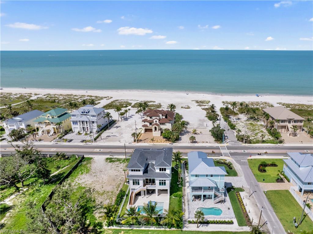 Overlooking the pristine sands of Fort Myers Beach, this BRAND NEW custom-built 3 story home by Imperial Homes offers the perfect blend of contemporary architecture and classic coastal charm. Designed as the ultimate luxury retreat, this 4,392 sq. ft. residence features 4 bedrooms and 4.5 bathrooms, with every detail thoughtfully curated to maximize panoramic Island/Gulf views, comfort, and elegance. Offered FULLY FURNISHED with design by Clive Daniel Home’s Sherie Weidner, the interiors reflect a modern take on “coastal vacation,” incorporating light natural woods, glass, and stone to create a truly unique and sophisticated atmosphere. From the moment you step inside, the open-concept layout captivates with high-end finishes, vaulted ceilings, and seamless indoor-outdoor integration. Floor-to-ceiling windows and multiple balconies frame breathtaking Gulf vistas, while the state-of-the-art chef’s kitchen, complete with top-tier appliances, a spacious island, and custom cabinetry, is ideal for both entertaining and everyday living. The luxurious primary suite serves as a private sanctuary, featuring a spa-like bathroom, walk-in closets, and a serene balcony. A separate game room, a striking rock wall fireplace, and a stylish martini lounge add to the home’s standout design. Outdoor living is elevated with a covered lanai, resort-style pool with spa, and beach access across the street, creating the ultimate setting for relaxation. Smart home technology allows for effortless control of lighting, climate, and security, ensuring modern convenience. Hurricane-resistant construction, impact-resistant windows, reinforced structural elements, and elevated foundations, this home is designed to withstand Florida’s weather. Energy-efficient features, including high-efficiency HVAC systems and smart irrigation, enhance sustainability without compromising luxury. This stunning home is a rare opportunity to own a piece of paradise on Fort Myers Beach in one of the best residential locations on the island!