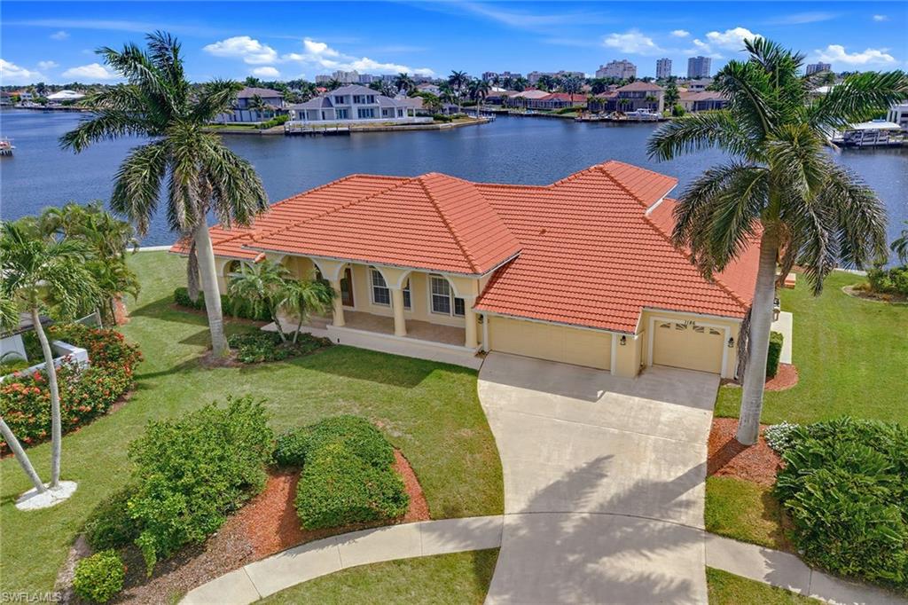 Exceptional waterfront living awaits with spectacular long water views and an impressive 162 feet of seawall. Designed to maximize its premier waterfront setting, this luxury residence blends sophisticated architecture with spacious living areas, abundant natural light and seamless indoor-outdoor living. Offering four bedrooms, three baths, a versatile loft and a three-car attached garage, this is a rare opportunity to own a thoughtfully designed waterfront retreat on Marco Island. Inside, soaring vaulted ceilings and an abundance of windows create a bright, open atmosphere throughout the home. Upon entering, you are welcomed into a spacious living room with volume ceilings and sliding glass doors that open to the screened lanai, filling the space with natural light. Toward the rear of the home, the expansive family room serves as the heart of the residence, offering dramatic vaulted ceilings and two sets of sliding glass doors overlooking the screened pool and spa. A formal dining room provides an elegant setting for entertaining, while the adjacent breakfast nook offers a relaxed space for casual dining with views of the outdoor living area. The spacious kitchen is designed for functionality and style, featuring generous countertop space, a large pantry and stainless steel appliances, including a refrigerator with ice maker, dishwasher, microwave and electric cooktop range, making it ideal for everything from casual meals to hosting family and friends. The first-floor primary suite is a private sanctuary filled with natural light and enhanced by wood flooring, a tray ceiling, spacious walk-in closets and sliding glass doors leading directly to the lanai. The luxurious en-suite bath features dual sinks, custom mirrors, a glass-enclosed walk-in shower, a separate soaking tub and a private water closet. A second guest suite includes an en-suite bath, closet, plantation shutters and carpeting, while the third and fourth guest bedrooms offer closets, carpeting, sliding glass doors to the lanai and convenient access to a full bath off the hallway. Upstairs, the flexible loft provides the perfect media room, game room or additional bedroom with the potential to serve as a fifth bedroom with its own bath. Sliding glass doors open to a private lookout deck, creating an inviting space to enjoy panoramic water views and coastal breezes. Outdoor living is designed to embrace the waterfront lifestyle with a screened pool and spa, a second-level porch overlooking the expansive water views and electric and manual storm shutters for added peace of mind. Completing the home is a well-equipped laundry room with a washer, dryer and utility sink. With its exceptional floor plan, premium waterfront setting and outstanding boating potential, this waterfront residence presents an extraordinary opportunity to enjoy the best of Marco Island living.