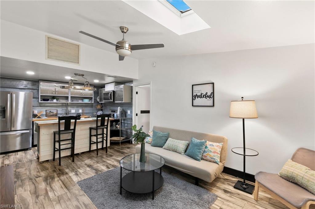 This updated end unit in Treetops of Naples offers easy, single-level living with no stairs or elevators. A long screened porch at the entry looks out onto sea grape and palms, a shaded, private place for morning coffee or an evening breeze. As an end unit, it backs onto greenery rather than a neighbor. Inside, vaulted ceilings and skylights keep the living area bright, and wood-look plank flooring runs through every room. The renovated kitchen has galvanized metal walls, butcher block counters, stainless appliances including a French-door refrigerator, roll-front cabinets with open shelving, and a rolling butcher block island with drawers and seating for two. The split bedrooms offer privacy, and each has its own bath. The first bedroom has a skylight of its own and a sliding barn-style door; the second has a wide closet and a window facing the greenery. Both baths have been updated with white shaker vanities, black fixtures, beadboard walls and patterned tile floors. A stacked washer and dryer is inside the unit, and the attic runs the full length of the home for extra storage. The condo is offered turnkey, so it’s ready to use from the first day. Treetops of Naples is a quiet, shady community with a pool and a shuffleboard court, and the unit has an assigned parking space just behind the building. Its location just off US 41 in South Naples keeps downtown Naples, shopping, dining, the beaches and Marco Island within easy reach.