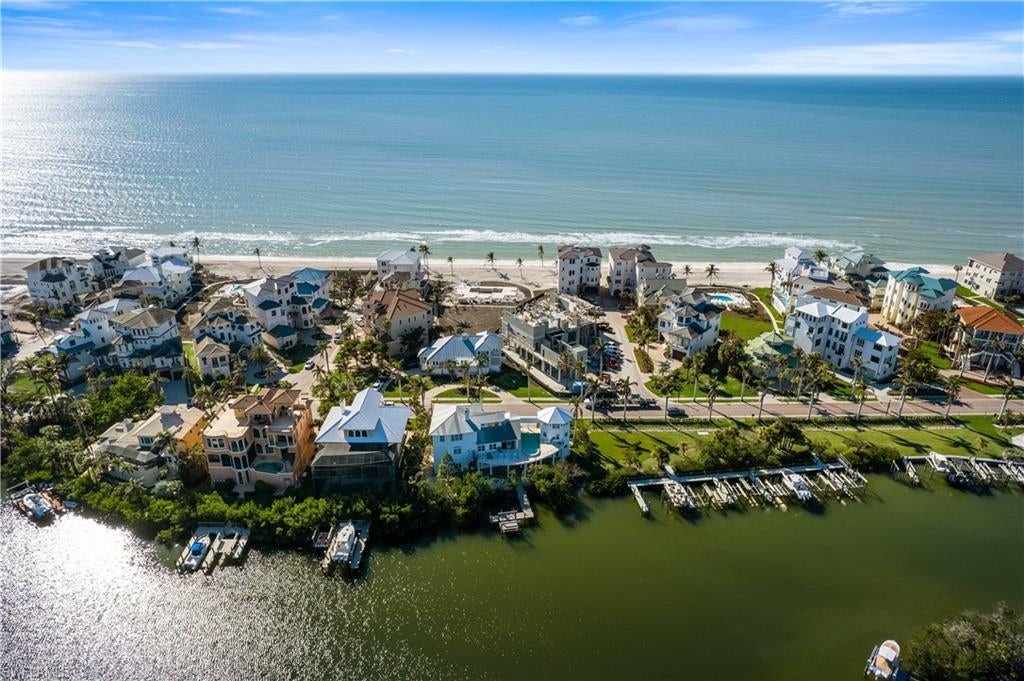 Beautifully renovated estate with breathtaking wide bay views in North Naples’ premier community of “Barefoot Beach”. A true boater and beach lover’s paradise, this home features deeded beach access only a 2-minute walk away and direct Gulf-access from your private dock with a brand-new boat lift. Every detail of this residence has been thoughtfully upgraded, including a new roof, elegant travertine and wood flooring, hurricane-impact windows and doors, and soaring coffered ceilings. Spanning 5,000 sq ft under air, this home offers 4 spacious bedrooms + a den, 4.5 bathrooms, a separate guest villa, dual laundry rooms, a private elevator and a ground-floor flex space. The outdoor space is truly an entertainer’s dream, offering sweeping bay views, an elevated pool and spa, an outdoor shower, and ample lounging areas—both covered and open. The oversized chef’s kitchen is a true masterpiece, featuring sleek quartz countertops, beautiful mahogany wood cabinetry, an induction cooktop, a breakfast bar, and an inviting eat-in area. The luxurious primary suite is a serene retreat, offering direct access to a private balcony overlooking the water—ideal for enjoying your morning coffee. A spacious office/sitting room, a fireplace, a wet bar with a built-in fridge, and a spa-like bathroom with dual vanities, a separate jetted tub, and a large frameless glass shower complete this tranquil sanctuary. The separate guest suite is perfect for hosting, offering 2 bedrooms, 2 bathrooms, and its own laundry facilities for added privacy. This is the epitome of coastal living. Optional membership to the exclusive "Club at Barefoot" provides access to tennis, two restaurants, beachside food and beverage service, and more. Conveniently located near fine dining, RSW Airport, Mercato, and Waterside Shops, and just 15 miles from the renowned Fifth Avenue in Naples, this home is a true gem in the heart of Barefoot Beach.