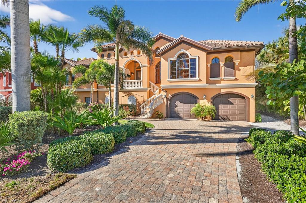 Riverfront tranquility meets beachside living at this custom-designed, three-bedroom, four-and-a-half-bath residence with a dedicated office, private pool and spa, and expansive outdoor living spaces. Set along the Sanibel River and directly across the street from the beach, this concrete-construction home is framed by lush tropical landscaping. A sweeping paver driveway, tiled roof, and graceful entry staircase create a memorable welcome.

Inside, marble floors, arched openings, detailed ceilings, and decorative glass bring character to the spacious layout. The central living room features a wood-burning fireplace, while a separate formal dining room provides an elegant setting for entertaining. The office offers rich custom cabinetry, built-in shelving, and an integrated desk.

The well-appointed kitchen features stainless steel appliances, double wall ovens, custom cabinetry, granite countertops, a breakfast bar, and pantry storage. An adjoining breakfast nook overlooks the outdoor living area, while a separate wet bar with glass-front cabinetry, a wine cooler, and an ice maker keeps entertaining effortless. The kitchen opens to a generous family room with a custom entertainment center, tray ceiling, and sliding glass doors framing peaceful river views.

Privately positioned on its own side of the home, the primary suite offers a spacious sitting area, direct access to the covered lanai, and multiple closets. Its inviting bath features dual vanities, a dressing table, a soaking tub beneath arched windows, and a separate walk-in shower. Two guest bedrooms occupy the opposite wing, creating comfortable separation for family and visitors.

Covered outdoor living areas extend across the rear of the home, offering room to lounge, dine, and enjoy the waterfront setting. A built-in outdoor kitchen with a gas grill, sink, and refrigerator makes alfresco meals easy. Below, a spacious screened enclosure surrounds the heated pool and raised spa, with a paver deck and tropical landscaping overlooking the river.

From quiet mornings watching the water to afternoons by the pool and sunset walks on the beach, this home brings the island lifestyle beautifully into focus.