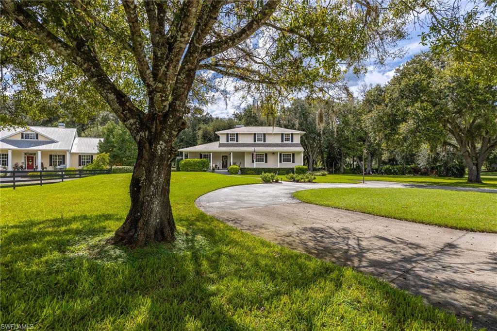 Welcome to this beautiful colonial-style home, set back on a beautifully landscaped 1.22-acre lot in the desirable Buckingham area of Fort Myers. With a classic wraparound front porch, mature oak trees, and a sweeping circular driveway, this 4-bedroom + den, 3-bath home offers timeless curb appeal and space to spread out, all with no HOA restrictions.

Inside, this 2,523 sq ft home features a traditional split-bedroom, two-story floor plan with generously sized living spaces throughout. The eat-in kitchen offers ample counter and cabinet space, a center island, and a full suite of appliances, opening into a warm family room with a wood-burning fireplace, the perfect gathering spot. A formal dining area with tray ceiling detailing adds an elegant touch for entertaining.

The primary suite offers a peaceful retreat with a spa-style en-suite bath featuring a separate soaking tub and shower, dual vanities, and abundant natural light. A versatile den/study provides flexible space for a home office, playroom, or additional living area, while the remaining bedrooms offer comfortable accommodations for family or guests.

Step outside to enjoy the screened and open lanai/porch areas overlooking the sprawling, tree-canopied backyard, an ideal setting for relaxing or entertaining amid mature landscaping and total privacy. Additional features include a paved circle drive, an extra building for storage, sprinkler system, well water with septic, and electric storm shutters.

With its combination of classic architecture, generous acreage, and a peaceful country-like setting just minutes from city conveniences, this Buckingham estate is a rare find for buyers seeking space, character, and privacy. Come see it for yourself!