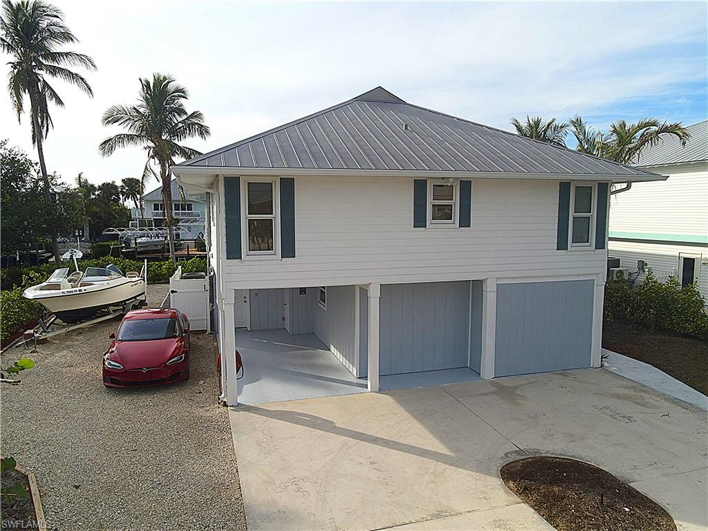 YOUR FLORIDA ISLAND ESCAPE AWAITS ! Imagine mornings on the water, afternoons exploring the Gulf, and evenings watching the most beautiful sunsets all from the balcony of your own private waterfront retreat. Now offered at $61,000 below the appraised value of $900,000, this exceptional waterfront home presents an outstanding opportunity to own in the highly sought-after boating community of Captain's Cove on Pine Island. As the only waterfront property currently available in this price range, it offers an unmatched combination of value, location, and direct Gulf access. Situated on the widest canal in Bokeelia, this elevated stilt home provides immediate, no-bridge access to Jug Creek in approximately one minute, with direct boating to Pine Island Sound, Charlotte Harbor, Boca Grande Pass, and the Gulf of Mexico. The upper level features an open, light-filled floor plan with three bedrooms, a den, two full bathrooms, and spacious living, dining, and kitchen areas that open to a large rear deck overlooking the canal—perfect for entertaining or enjoying breathtaking sunsets. The updated kitchen includes brand new 2025 appliances, including the refrigerator, range, microwave, and dishwasher. The lower level offers incredible flexibility with its own private entrance, full kitchen, living area, bedroom, full bath, laundry room, enclosed patio, workshop with sliding barn doors, and abundant storage. Ideal for guests, extended family, a home office, or potential rental opportunities. Designed for the waterfront lifestyle, the private dock features a 10,000-pound boat lift with a Coastline Boat Lift Covers steel-framed canopy, blue dock lighting, and a KayaArm kayak launch system. The property also offers ample space for vehicles, an RV, boat trailer, and recreational equipment, along with an oversized 80' x 20' limestone driveway with professional underlayment and mature clusia privacy hedges. Over $100,000 in recent improvements include more than 60 clusia privacy plants, hibiscus landscaping, a producing navel orange tree, screened rear porch, enclosed carport conversion with future living potential, granite walkways with custom edging, decorative shutters, lighthouse mailbox, remodeled upstairs bathroom, and a newer upstairs A/C system with updated ductwork. Combining immediate Gulf access, one of Pine Island's widest canals, flexible living space, and extensive upgrades, this move-in-ready home offers an exceptional opportunity to enjoy the Southwest Florida waterfront lifestyle. THIS PROPERTY WILL NOT LAST LONG!