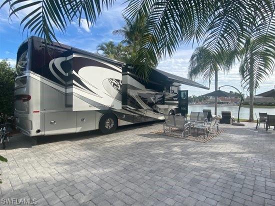 Bring you Class A motorhome and pull into this south facing site looking over the lake with a wide-open view! This site is fully upgraded with neutral gray pavers expanding to make a large patio area with raised edging to finish off a clean, modern look.  The property is surrounded by tropical landscaping including different types of palms and bushes. This site includes a 10x10 coach house that has recently been finished with a new stucco exterior, wrap around awning, and tile roof upgrade.  The interior is finished with a sink, toilet and shower with plenty of room for a queen pull out. Very usable space! Take advantage of this move in ready property!