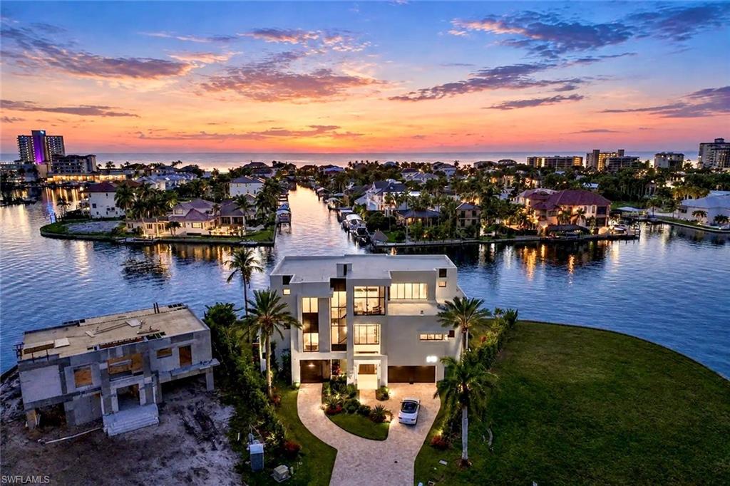 From the moment you turn onto Seagull Ave, the promise of waterfront living comes into view-leading you to your own private fortress nestled at the end of the quiet, picturesque cul-de-sac! A remarkable combination of architectural presence & piece of mind, plus refined coastal luxury, this extraordinary residence offers an elevated living area situated an impressive 18.5 FEET above sea level, complimented by a Kohler whole-home generator! Built in 2025, this astonishing tri-level waterfront estate showcases cutting-edge architecture, remarkable craftmanship, and thoughtfully selected natural materials, all set on a distinctive pie-shaped homesite w/wide, exceptionally long unobstructive water views & coveted western exposure for Naples' legendary sizzling sunsets! Inside, dramatic floor to ceiling glass walls fill interiors with natural light while framing sweeping water vistas evolving beautifully throughout the day. Beyond its striking aesthetics and dynamic water views, this residence offers exceptional structural integrity, featuring solid precast concrete floor slabs reinforced with steel for added strength & stability! An exceptional blend of luxury, design and the ultimate SW Florida boating lifestyle! Featuring direct Gulf access & a covered boatslip accommodating a present 33 ft Boston Whaler Outrage plus a large deck which continues to 2 jet-ski slips, this home is designed for those who appreciate the freedom of life on the water! Inside, dual primary suites with balconies, breakfast bars, a private elevator, premium finishes, and a rare 5 car garage plus ample flex spaces provide an exceptional level of convenience & functionality. An expansive floorplan offers multiple en-suite bedrooms...designer bathrooms impress with textured shower walls, decorative glass cabinet panels plus view oriented soaking tubs! Outdoors, discover a resort inspired retreat with a sparkling pool & spa, boasting mood-relaxing fire features, a fully equipped outdoor kitchen w/ a Wolf grill & bar, & captivating Western facing water views which provide a beautiful Naples sunset backdrop! The chef inspired kitchen is a showpiece in its own right featuring custom Chicago-crafted cabinetry, exquisite/abundant Cristallo quartzite countertops AND backsplash, Wolf appliances, Sub Zero beverage drawers, an icemaker, dual dishwashers, an eye-opening spacious pantry, and an expansive island w/breakfast bar. Italian luxury porcelain wood flooring and several thoughtfully placed private seating areas throughout along with a dramatic living area fireplace which flickers beneath a modern, sculptural chandelier further enhance this home's sophisticated aesthetic! A temperature-controlled wine showcase provides the finishing touch to this extraordinary waterfront residence! Enjoy a nearby private beach club membership @ Paraiso! Elevated living, architectural substance, boating convenience & extraordinary waterfront entertaining all create an irresistible place to call home!