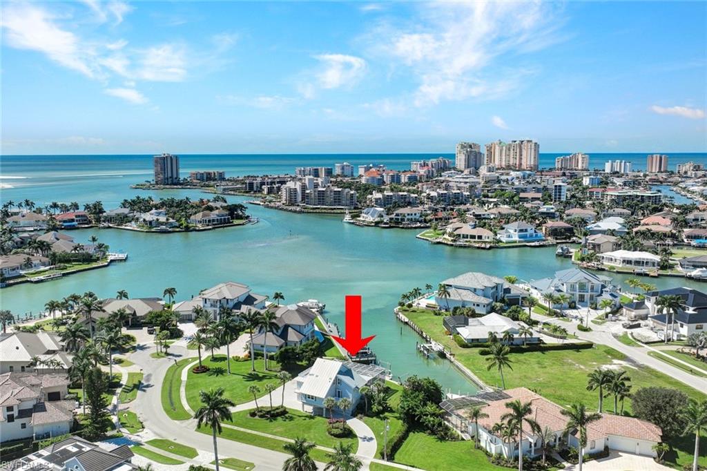 Experience the best of island living in this rare Marco Island Estates property, offering southwest rear exposure and tranquil water views along Smokehouse Creek with quick, direct access to the Gulf of Mexico. Set on an impressive half-acre lot, this four-bedroom, three-and-a-half-bath home combines timeless charm with thoughtful modern updates. A long brick-paver circular driveway leads to an oversized three-car garage and a covered parking area for guests, creating a welcoming first impression. Inside, the home has been beautifully maintained and enhanced over the years. The kitchen remodel completed in 2017 features custom cabinetry, quartz countertops, stainless steel appliances, and under-cabinet lighting, offering both style and functionality. In the living area, a dry bar and wine cooler make entertaining a pleasure. The residence offers two primary suites, each with private outdoor access. The main-level suite includes a spa-inspired bathroom with dual sinks, a jetted tub, and a separate shower, while the second main-floor guest suite opens to a private balcony. Upstairs, another spacious primary suite showcases new LED lighting, a large walk-through closet, and a private balcony that overlooks the beautiful waterway. The pool with screened lanai is perfectly positioned to capture the sun throughout the day due to its southwest exposure. A wraparound lanai deck provides multiple seating areas to enjoy the gentle breeze, the sunsets, and the peaceful water views. Recent updates include a new living room electric shutter in 2024, new garage doors 2022, impact windows 2018, and reinforced seawall and pilings 2015. Additional improvements include shower glass doors, updated AC and hot water heater, and an ADT security system. Private dock and lift and just minutes from open Gulf waters. Surrounded by some of Marco Island's most luxurious waterfront properties, this home represents an exceptional opportunity to create your own piece of paradise. The property is being offered as-is.  Owner has Flood Insurance.