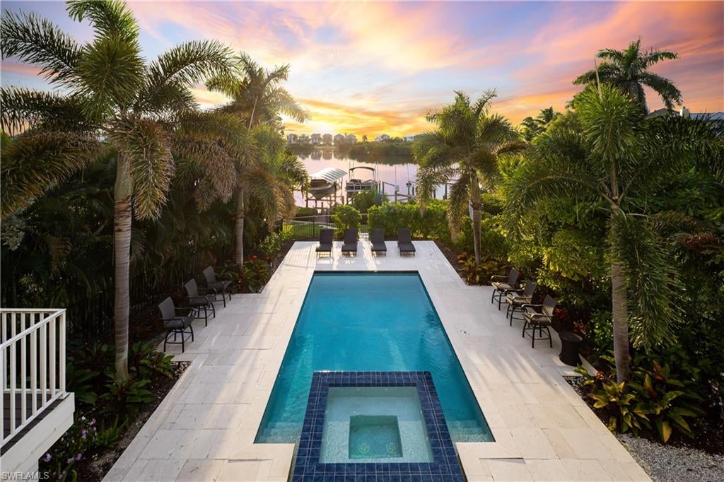 Stunning bayfront masterpiece in the coveted “Carolands” neighborhood on Bonita Beach! Experience beautiful bay views and spectacular sunsets from this coastal contemporary retreat, perfectly positioned with highly desirable Western exposure. A true beach and boater’s paradise, this property is just a 15-minute walk (0.7 miles) to the pristine sands of Bonita Beach and offers quick Gulf-access with the ultimate boating setup—including a private dock with dual lifts for effortless days on the water. Built like a fortress in 2017, this home was crafted with hurricane impact windows/doors and electric storm shutters. Every detail was carefully curated, from beautiful wide-plank oak flooring to custom coffered ceilings. Inside, the open floor plan spans 5,015 sq ft under air, featuring 5 bedrooms (including a VIP suite), 4 full and 3 half baths, dual laundry rooms, and a 3-car garage. The chef’s kitchen boasts quartz countertops, sleek white cabinetry, top-of-the-line Thermador appliances, and a gas range, with an adjacent formal dining area with a bar and wine fridge. Expansive fully pocketing sliders open to the lanai, creating seamless indoor-outdoor living. The outdoor oasis features a summer kitchen, fireplace, and electric screens overlooking a resort-style pool and spa with stunning bay views—perfect for entertaining or relaxing in privacy. The main floor primary suite offers direct lanai access and a spa-like bath featuring dual vanities, a freestanding tub, and a glass-enclosed shower. Upstairs, enjoy a second living area with a wet bar, additional laundry room, a VIP suite, and a spacious top-floor lanai overlooking the bay. Additional highlights include a private elevator, 24kW whole-house generator, smart home technology, and ground-level flex space. With no HOA fees or rental restrictions, this property presents an excellent opportunity as a full-time personal residence, seasonal retreat, or a lucrative investment property. Ideally located near top dining and shopping, just minutes from Mercato, The Promenade, Waterside Shops, Coconut Point, 5th Avenue, and the International Airport.