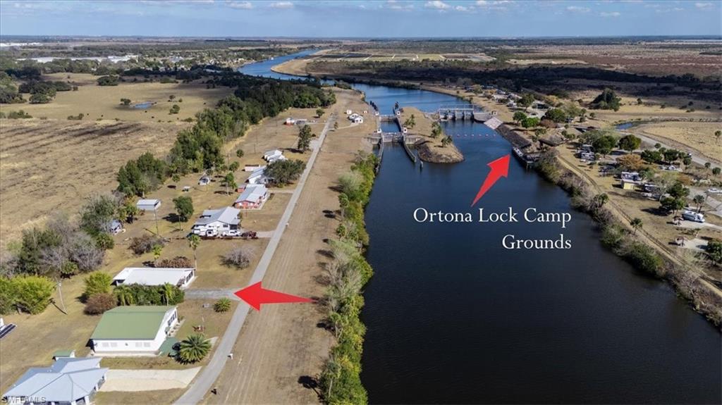 Price Improvement | Exceptional Value for Riverfront Lifestyle Living
RV-Port House with Full Hook-Ups | River Views Near Ortona Locks

This concrete block home with a metal roof offers scenic views of the Caloosahatchee River and historic Ortona Lock, providing the benefit of riverfront living without the added tax burden of direct waterfront ownership. Located along the Caloosahatchee River—the intracoastal waterway connecting Florida’s east and west coasts—you can enjoy passing boats, colorful sunsets, and peaceful water views from the screened front lanai and elevated upper deck.

Designed for a variety of homeowners, including RV enthusiasts, seasonal residents, and full-time occupants, this 2-bedroom, 2-bath residence sits on a .43-acre lot and features an oversized RV port with full hook-ups, accommodating large Class A motorhomes, fifth wheels, campers, and travel trailers. The covered structure provides protection and convenience for your recreational vehicle and is also ideal for keeping a boat sheltered under the roof of the port, adding flexibility for both land and water enthusiasts while maintaining the comfort and character of a traditional single-family home.

Outdoor living is a defining feature, highlighted by a fully screened, south-facing lanai that captures cool breezes and river views. The upper viewing deck provides an elevated vantage point to watch boats travel along the Caloosahatchee River while enjoying beautiful sunrises and sunsets.

The private guest bedroom and bath include a separate entrance and screened lanai, ideal for multi-generational living, extended guests, or added privacy.

River access is approximately 100 yards away at the Ortona Lock Boat Ramp, a free public ramp and day-use park located at the end of Lock Lane. Enjoy excellent fishing, boating, and miles of nearby walking and biking opportunities.

High-speed fiber optic internet is available. Conveniently located about 15 minutes from LaBelle, with easy access to State Road 29 and U.S. Route 27, this property offers a quiet rural setting with practical connectivity.

An additional .48-acre adjacent lot is available under specific terms: the vacant lot will not be sold prior to the home sale. This presents a unique opportunity for expansion or added privacy.

Opportunities like this—combining RV infrastructure, boating access, and river views—are increasingly hard to find at this value point.