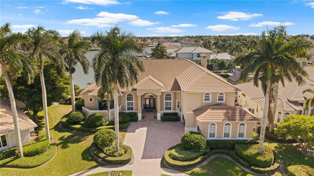 EXCEPTIONAL BAYFRONT ESTATE WITH BREATHTAKING WATER VIEWS AND SOUTHERN EXPOSURE! Experience luxurious waterfront living in this magnificent 5-bedroom, 6-bath estate overlooking the sparkling waters of Roberts Bay, with quick, direct boating access to the Gulf. Custom-built by renowned Slocum-Christian Builders with superior Epicore construction, this extraordinary residence showcases exceptional craftsmanship, architectural elegance, and exquisite attention to detail throughout. Soaring ceilings, magnificent walls of glass, intricate ceiling treatments, custom cabinetry, and expansive living spaces frame spectacular, unobstructed bay views while seamlessly blending indoor and outdoor living.
The beautifully remodeled kitchen (2021) is designed for both culinary enthusiasts and effortless entertaining, featuring solid wood cabinetry, a Sub-Zero refrigerator, gas cooktop, premium cooking appliances, and a spacious pantry. An elegant dining room with a striking tile-accented gas fireplace creates an inviting ambiance, while the richly wood-paneled den offers a sophisticated private retreat.
The luxurious first-floor primary suite is a sanctuary of comfort, featuring generous space for a sitting area, captivating water views, and direct access to the pool and lanai boasting an expansive closet accenting high-end built-ins, accent lighting, and high-end features. The stunningly remodeled primary bath (2025) showcases elegant cabinetry, designer lighting, updated plumbing fixtures, a spectacular tiled walk-in shower, smart toilet/bidet, and remote-controlled blinds. Upstairs, an expansive entertainment loft with a convenient morning kitchen and private balcony provides an inviting gathering space overlooking the resort-style pool and breathtaking bay.
OUTDOOR LIVING IS NOTHING SHORT OF SPECTACULAR! Southern exposure bathes the magnificent two-tier lanai in sunshine, creating an idyllic tropical paradise complete with a sparkling pool and spa, fully equipped outdoor kitchen, and expansive covered seating and entertaining areas. Boating enthusiasts will appreciate the impressive 184-foot waterfront dockage, boat lift, and charming octagonal fishing dock, all perfectly positioned to enjoy the protected waters of Roberts Bay and direct access to the Gulf.
Additional highlights include exceptional storage, a new roof (2020), hurricane-impact windows and shutters (2023), a beautifully modernized front entry (2022), a buried propane tank servicing the gas cooktop, fireplace, and outdoor grill, and a generator. Situated on a meticulously manicured tropical homesite with an approximate elevation of 12.3 feet, this exceptional property offers privacy, elegance, and the ultimate Southwest Florida waterfront lifestyle. Ideally located near Marco Island's pristine beaches, exceptional dining, boutique shopping, and recreational amenities, this remarkable estate presents a rare opportunity to experience waterfront luxury at its finest.