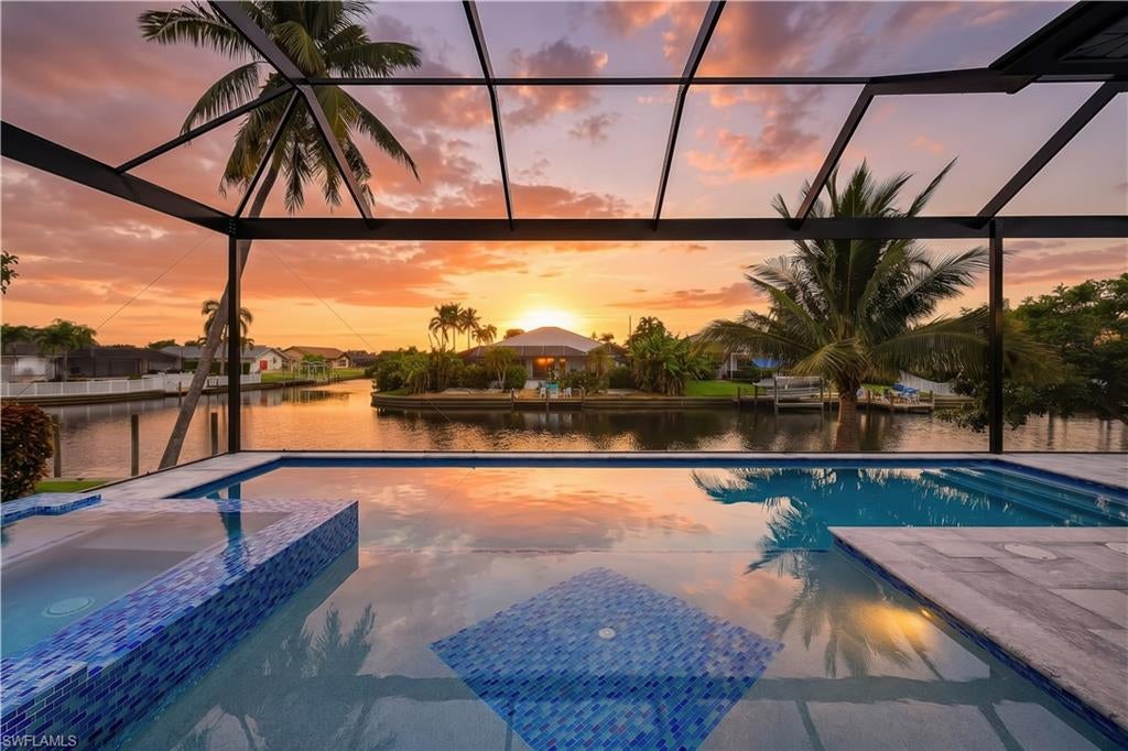 Experience the pinnacle of Southwest Florida waterfront living in this stunning, turnkey, new construction home located on a Gulf access canal in beautiful SE Cape Coral. Showcasing sleek contemporary architecture and exceptional craftsmanship, this four-bedroom plus den, three-bathroom residence offers the perfect blend of luxury, comfort, and functionality. From the moment you arrive, the clean lines, modern façade, and spacious three-car garage set the tone for what awaits inside. Step through the impact-resistant double doors and into a bright, open-concept floor plan designed to maximize natural light and breathtaking canal views. Expansive impact-resistant windows and sliding glass doors seamlessly connect indoor and outdoor living spaces while providing peace of mind and energy efficiency. The heart of the home is the impressive modern kitchen, thoughtfully designed with both style and practicality in mind. Featuring sleek cabinetry, Cafe appliances, premium countertops, a large center island, and ample storage, this space is ideal for entertaining or everyday living. The kitchen flows effortlessly into the spacious living and dining areas, where a giant contemporary tiled fireplace creates a dramatic focal point and adds warmth and sophistication to the space. Tile flooring runs throughout the entire home, offering a cohesive look that is both elegant and easy to maintain. The luxurious primary suite is a private retreat with serene canal views, generous proportions, and a spacious walk-in closet. The spa-inspired primary bathroom features upscale finishes, dual vanities, and a beautifully appointed shower designed for relaxation. Three additional bedrooms provide comfort and flexibility for family and guests, while the dedicated den offers the perfect space for a home office, media room, or additional guest area. The garage includes tiled floors, an EV charging wall plug, and split-unit AC. Step outside to your private waterfront oasis. The expansive screened lanai encloses a sparkling saltwater pool and heated Jacuzzi, creating the ultimate year-round retreat. Whether you are enjoying a morning swim, relaxing in the spa at sunset, or hosting weekend gatherings, this outdoor living space is designed to impress. The fully equipped outdoor barbecue area makes entertaining easy, while the picturesque canal view provides a tranquil and scenic backdrop. With direct Gulf access, boating enthusiasts will appreciate the convenience and lifestyle that come with living on the water. This exceptional Gulf access property offers the very best of contemporary waterfront living in one of Florida’s most desirable coastal communities. Whether you are seeking a primary residence, seasonal retreat, or investment opportunity, this remarkable home delivers style, comfort, and the ultimate Florida lifestyle.
