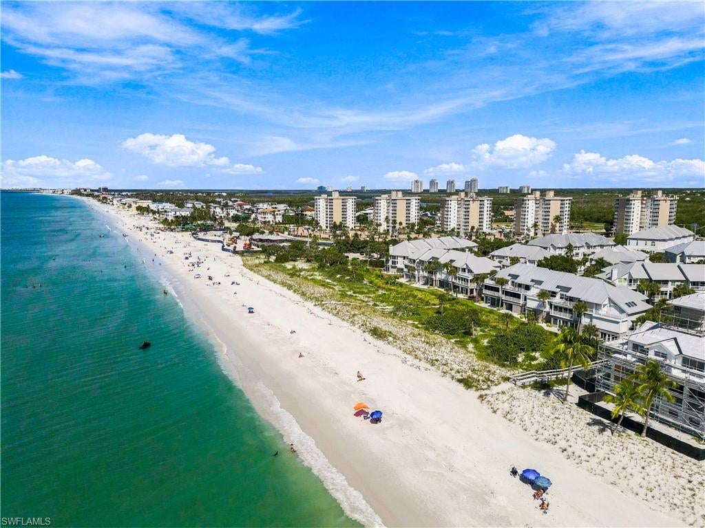 Beautiful villa with partial Gulf views, nestled within the highly sought-after Barefoot Beach community in North Naples! Enjoy the sugar-white sands and stunning turquoise waters of the Gulf just steps from your door, with private beach access exclusively for residents! This spacious, concrete-block villa offers approximately 2,800 square feet under air, featuring 3 bedrooms plus a den, 3.5 bathrooms, multiple living areas, a PRIVATE ELEVATOR providing access to all three levels, a 2-car garage, hurricane impact windows, and electric shutters. Interior features include soaring 11-12 foot ceilings, illuminated coffered tray ceilings, custom molding, tile and hardwood flooring, plantation shutters, and oversized windows that fill the home with natural light. The main living level, situated on the third floor, features an expansive great room and an additional living area with a cozy fireplace. Beautiful French doors open to a spacious wraparound balcony, where you can enjoy refreshing Gulf breezes, partial Gulf views, and spectacular sunset skies. The spacious kitchen features a reverse osmosis water filtration system and opens to the adjacent dining and living areas—ideal for entertaining family and friends. The expansive primary suite serves as a private retreat, featuring beautiful hardwood flooring, plantation shutters, and an ensuite bath with dual sinks, separate tub, and walk-in shower. Additional features include generous air-conditioned storage space and a whole-house water softener system. The Villas at Barefoot Beach offer resort-style amenities, including two pools, a spa, 24/7 roving security, and private beach access via a community boardwalk just steps from your door. Optional membership to the exclusive Club at Barefoot Beach offers access to tennis courts, two restaurants, and beachside and poolside food and beverage service. Ideally situated near world-class dining, upscale shopping at Mercato and Waterside Shops, Southwest Florida International Airport, and the renowned boutiques and restaurants of Fifth Avenue South, this exceptional villa offers the perfect opportunity to enjoy the coveted Barefoot Beach lifestyle!