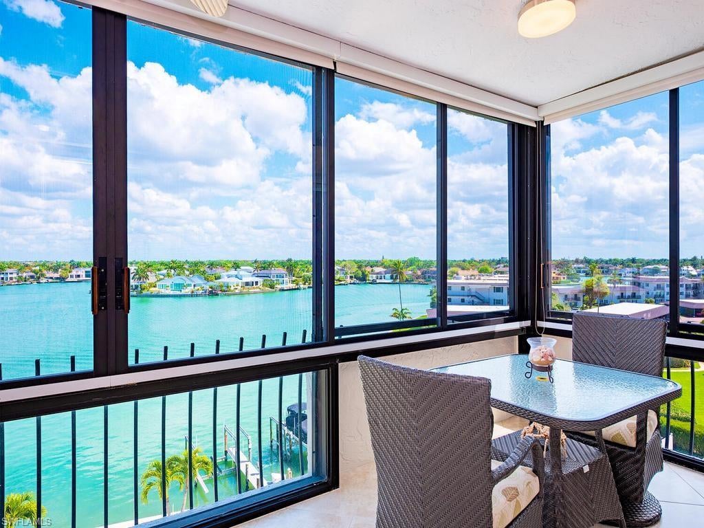Panoramic Venetian Bay views from the 24' glass lanai! Move-in ready furnished condo featuring high-quality finishes throughout.  Highlights include new HVAC and water heater in 2026, white oak floors, bar with wine cooler and electric window shades and hurricane shutters on the lanai. Impact resistant sliding glass doors and windows in the bedrooms. The open kitchen offers granite waterfall counters, Italian cabinetry, and premium stainless appliances. Both bedrooms have walk-in closets and remodeled baths with a split plan for privacy. The condo includes garage parking and extra storage. Madrid Club offers many amenities including a bayfront pool, gym, social & card rooms, pool side pavilion with outdoor kitchen, kayak racks, and a floating dock. Steps from the beach and nearby Village on Venetian Bay dining and shopping. Location, Beauty, Value!