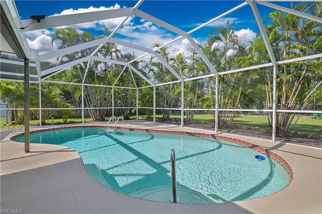 **HEATED POOL HOME IN SOUTHWEST CAPE CORAL – NO FLOOD ZONE, NO HOA & ASSESSMENTS PAID!** This updated 3-bedroom, 2-bath home offers an open, spacious floor plan with vaulted ceilings, a split-bedroom design, and plenty of natural light. The kitchen features wood cabinetry, stone-finish countertops, stainless steel appliances, an island with breakfast bar seating, and a convenient built-in desk area. Recent improvements include a **NEW ROOF (2022), updated bathrooms and luxury vinyl plank flooring in the bedrooms.  This home offers additional peace of mind with storm protection upgrades like IMPACT WINDOWS, hurricane rated front door and hurricane rated garage door with storm shutters for lanai.  Sliding glass doors open to a large covered lanai and screened-in, electrically heated swimming pool, providing plenty of space for outdoor dining and entertaining. The oversized backyard offers mature palm trees and additional green space beyond the pool enclosure. Situated on an approximately 10,000-square-foot lot in desirable Southwest Cape Coral, this home offers central water and sewer with assessments paid, no HOA fees, and a location outside the designated flood zone. With its practical floor plan, important updates, and generous outdoor living space, this property is ready for its next owner!
