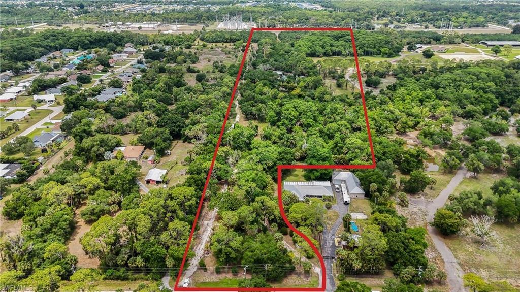 NORTH FORT MYERS | 13.37 ACRES | AG-2 | DUAL PARCEL | OLD BAYSHORE ROAD

Rarely does an opportunity like this come to market. Thirteen-plus contiguous, fully fenced acres — two adjoining parcels sold together — positioned directly across from the Lee County Civic Center along one of Southwest Florida's most active growth corridors. With 207 feet of frontage on Old Bayshore Road, dual commercial-grade access points, and AG-2 zoning, this is a strategically timed acquisition for developers, investors, and owner-operators looking to capitalize on the explosive expansion reshaping North Fort Myers.

The location alone tells the story. Situated squarely within the SR-31/Bayshore corridor connecting to Babcock Ranch — consistently ranked among the nation's top-selling master-planned communities — this property sits at the intersection of where Southwest Florida is heading. Substantial residential, commercial, and infrastructure investment is already underway in every direction.

The infrastructure is ready to work. Two gated entry points capable of handling semi-trailers, heavy equipment, RVs, and large machinery. Public water service to both the residence and barn. A separate irrigation well. A 900-gallon septic system. And a fully equipped 2,400 sq ft pole barn (built 2013) with concrete floors, 120V/230V electric, city water, full bath, tack room, hay loft, and three oversized 14-foot bay doors. This isn't raw land — it's a fully operational platform ready for immediate use or repositioning.

The residence delivers livability at scale. The elevated custom home (built 2011, approx. 1,940 sq ft under air) features concrete block first-floor construction, metal roof, tile throughout, oversized dual-bay garage, covered lanai with hot tub, and sweeping views over the fenced acreage and two onsite ponds — one natural protected wetland, one man-made.

Current use is already income-aware. Approximately 3 acres operate as an active tree farm with existing agricultural exemption benefits — keeping carrying costs lean while longer-term development or repositioning plays out.

No easements impacting the property. Survey on file.

Ideal for: Land banking | Residential development | Commercial development | Agricultural or equestrian operations | Contractor/nursery/landscaping headquarters | RV & equipment storage | Live-work compound

Minutes to: I-75 | Downtown Fort Myers | Punta Gorda | Babcock Ranch/SR-31 expansion corridor