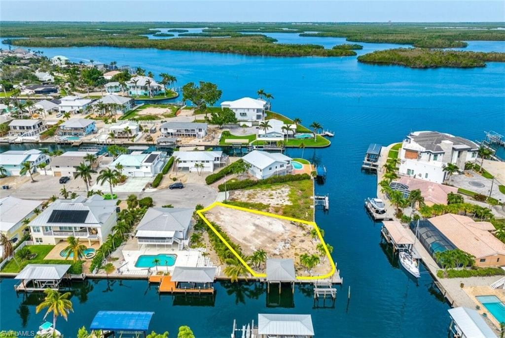 One or more photo(s) has been virtually staged, AI generated or rendered.  One or more photo(s) has been virtually staged, AI generated or rendered. Introducing an EXTRAORDINARY Waterfront NEW CONSTRUCTION opportunity on a .21 Acres Gulf-access homesite. Boasting an IMPRESSIVE 140 feet of Gulf Access Canal frontage, this OVERSIZED estate-sized parcel offers an exceptionally rare combination of expansive water frontage, direct Gulf access, and breathtaking bay views. The nearby Direct Beach access offers unlimited sunsets and beach walks.

Situated at the end of a quiet cul-de-sac, this premier boating location provides quick, convenient access to open waters, making it a true boater's dream. With ample space to design and build a custom luxury waterfront residence, the property offers endless possibilities for creating a private coastal retreat tailored to your lifestyle.

Assemblage opportunity at 18 & 20 Avenida Carita. Purchase separately or as a package of 2 properties with lot 20 adjacent to it, to build your waterfront island compound (or two homes if you wish) on these oversized canal lots with a combined size of .37 acres. Lot 18 features a boat lift, private dock, and a grandfathered waterfront structure with a metal roof, adding unique character and flexibility rarely found on island properties. The covered boat lift is complemented by an additional open-air lift with dedicated space for both a boat and personal watercraft. Lot 20 offers its own separate boat lift and dock, providing extensive dockage for multiple vessels and an unparalleled waterfront experience.
MULTIPLE BUILDER INTRODUCTIONS AVAILALBE.
The generous homesite showcases stunning water vistas from multiple vantage points and provides abundant room for outdoor living, resort-style amenities, and extensive waterfront dockage. Whether you're an avid boater, waterfront enthusiast, or simply seeking an unparalleled Southwest Florida setting, this one-of-a-kind property presents a rare opportunity to create a legacy estate in an exceptional Gulf-access location.