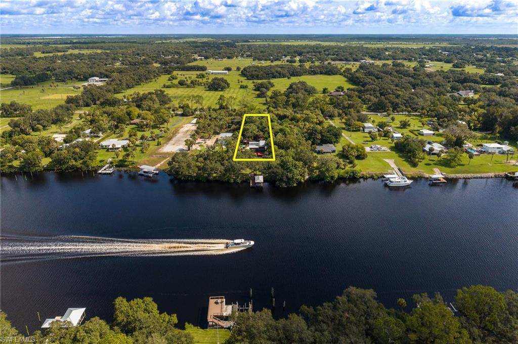 NEW PRICE - A rare opportunity to own 1.24+/- private acres directly on the Caloosahatchee River in historic Fort Denaud. This distinctive three-level riverfront retreat offers 4 bedrooms, 3.5 baths and approximately 2,599 square feet, blending extensive updates with the warmth and character of Old Florida. Steel-beam construction, restored original cedar siding and beautiful cypress/pecky-cypress details create a home that feels truly one of a kind. The property is designed for the boating lifestyle, with deep-water dockage, a covered boathouse and a 29-foot boat lift providing direct access to the Okeechobee Waterway. Inside, the flexible ground level includes a kitchen and full bath, creating excellent possibilities for guests, extended family, a private in-law arrangement or secondary prep space. Outside, mature tropical gardens, bamboo privacy, flowering specimens, herbs and fruiting plants surround the home and create a private botanical setting along the river. Gated entry, expansive porches and unforgettable waterfront sunsets complete the experience. This property can serve beautifully as a full-time residence, seasonal riverfront escape or flexible second-home opportunity. Buyers interested in any short-term rental or income-producing use should independently verify applicable zoning, licensing, tax and rental requirements. Minutes from the historic Fort Denaud swing bridge and convenient to LaBelle, Fort Myers and Southwest Florida destinations. This is not the typical waterfront home - it is a private Old Florida river retreat built around boating, privacy, character and lifestyle.
