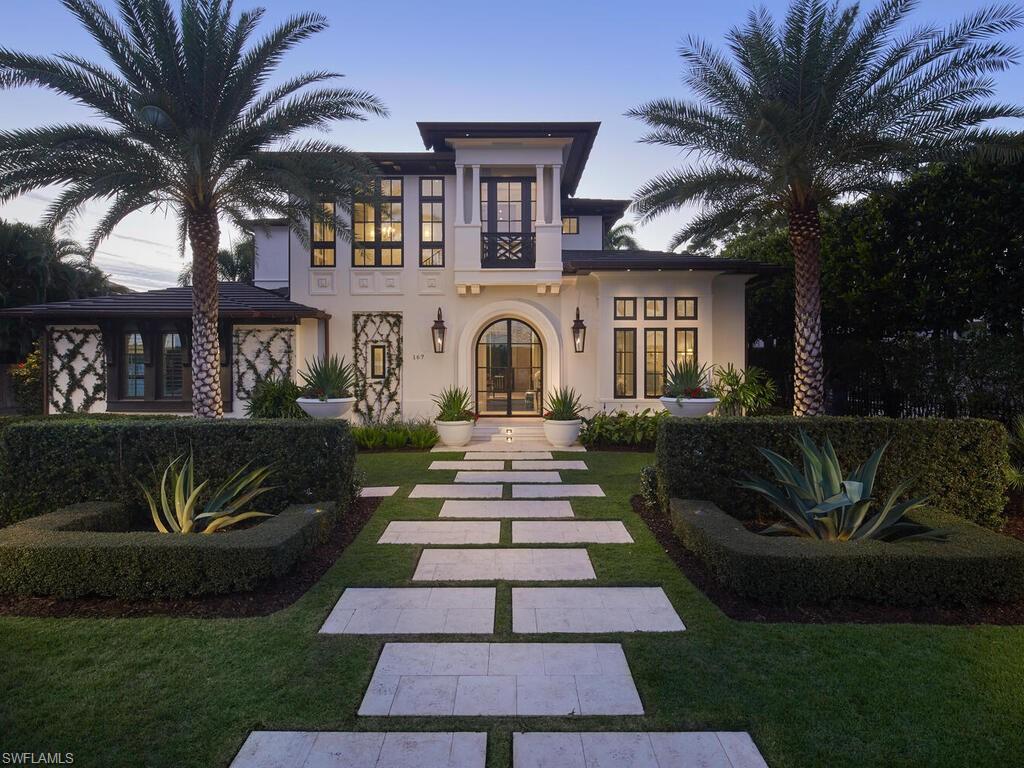 Located on a quiet street in the heart of Old Naples, this exceptional custom home by London Bay pairs timeless architecture with exquisite interiors by Romanza Interior Design. Completed in 2020, the residence showcases meticulous craftsmanship and distinctive details, including an arched glass front door, a faux Juliet balcony, decorative medallions, copper gutters, gas lanterns, and a mitered tile roof, all framed by beautifully maintained landscaping. Venetian plaster extends throughout the first floor, where a thoughtfully designed kitchen, butler’s pantry with wet bar, spacious great room, and formal dining area are enhanced by custom built-ins. The luxurious primary suite offers direct access to the rear yard, two custom walk-in closets, and a beautifully appointed bath. Upstairs, two guest suites, a study that accommodates additional sleeping space, and a loft opening to a generous covered balcony provide inviting spaces for family and guests. The private rear yard offers a vibrant, landscaped retreat with casual seating, alfresco dining beneath an illuminated trellis, and an intimate fire pit area. Additional features include automated shutters and screens, elevated generator and air-conditioning units, tankless water heaters, natural gas service, and an air-conditioned garage with a car lift and adjacent storage closet. An exceptional opportunity to enjoy Old Naples living, close to the beach and downtown’s celebrated shopping and dining.