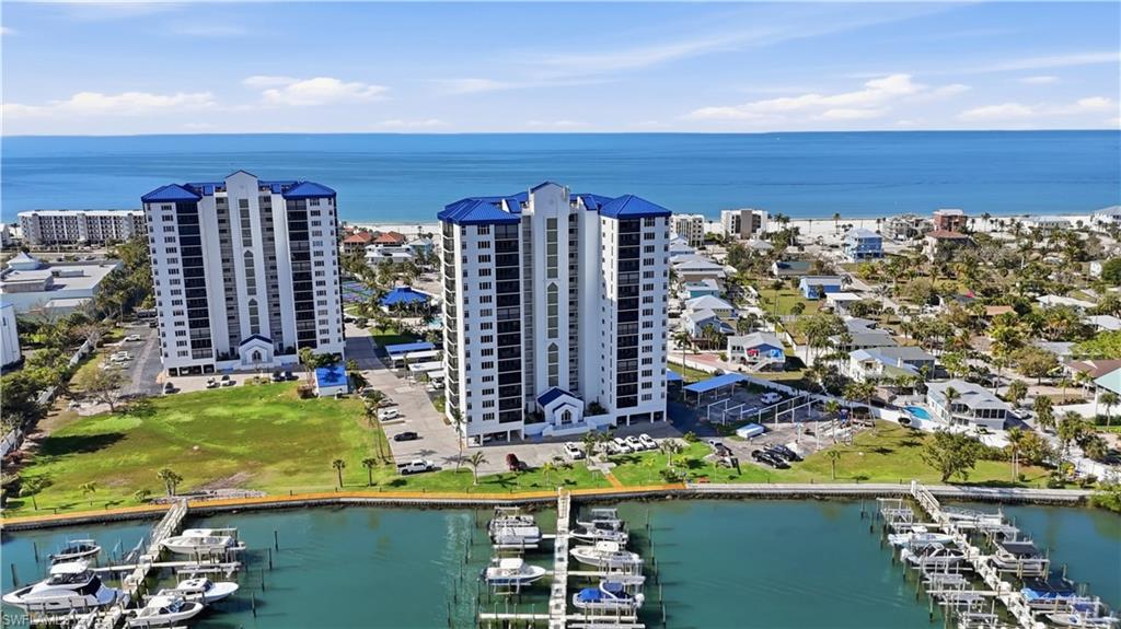 One or more photo(s) has been virtually staged, AI generated or rendered.  Discover exceptional waterfront living at OCEAN HARBOR, one of Fort Myers Beach's most desirable communities, where PANORAMIC GULF AND BAY VIEWS provide a spectacular backdrop to everyday life. This beautifully furnished 2-bedroom, 2-bath condominium offers an inviting blend of coastal elegance, comfort, and convenience. Perched on the 5th floor, the residence captures stunning views of Estero Bay and magnificent Gulf sunsets, with water visible from every window. Offered TURNKEY and move-in ready, the interior features elegant marble flooring, tasteful furnishings, and a spacious, open-concept floor plan designed to maximize natural light and showcase the surrounding scenery. The generous living and dining areas connect effortlessly to a well-equipped kitchen, creating an ideal setting for both entertaining and relaxed island living. An expansive glass-enclosed lanai with hurricane-rated sliders provides additional living space and the perfect vantage point to enjoy the changing colors of the Gulf and Bay throughout the day. NEWLY INSTALLED CAT 5 IMPACT-RATED GLASS THROUGHOUT provides enhanced storm protection, security, and peace of mind. Additional conveniences include TWO DEDICATED PARKING SPACES and extra building storage, valuable features for condominium living on the island. Ocean Harbor offers an impressive collection of resort-style amenities, including a swimming pool, two jacuzzi spas, tennis and pickleball courts, bocce, a clubhouse with full kitchen, dog park, and beach access, all surrounded by lush tropical landscaping. Ideally positioned in the heart of Fort Myers Beach, the community is just steps from Publix, waterfront dining, popular restaurants, and a full-service marina, with the island's renowned white-sand beaches only a short walk away. Whether enjoying morning coffee overlooking the Bay, an afternoon at the beach, or unforgettable sunsets over the Gulf, this residence delivers the quintessential Southwest Florida coastal lifestyle. An exceptional opportunity to own a beautifully maintained waterfront retreat with outstanding views, desirable amenities, and an unbeatable island location.