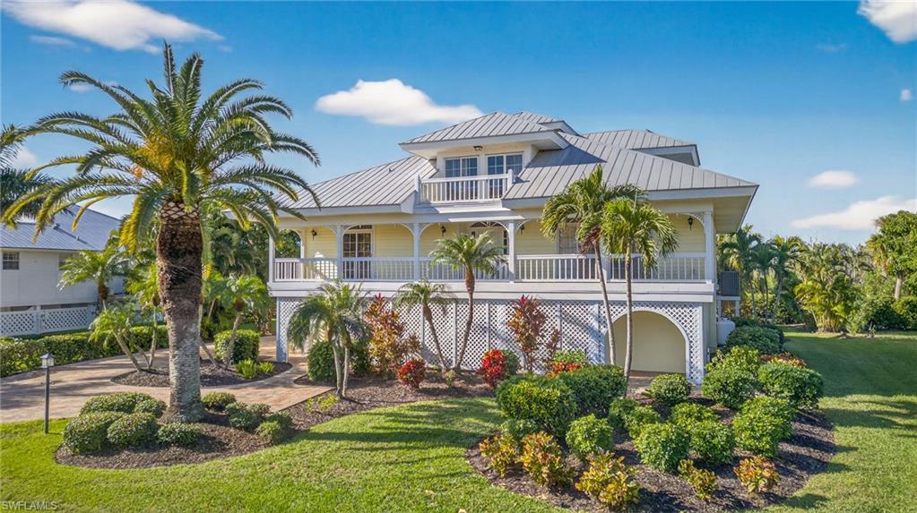 Wide lake and golf course views set the scene for this elevated four-bedroom, three-bath home on a quiet cul-de-sac in Sanibel’s sought-after Dunes community. Tropical landscaping, welcoming porches, and a private pool complement a spacious interior filled with natural light and classic island character.

Soaring ceilings with exposed wood beams, warm wood flooring, and an open upper gallery give the main living area a distinctive, airy feel. The generous living and dining spaces flow together, with large windows and sliding glass doors drawing your attention to the water beyond. An expansive screened lanai wraps around two sides of the living area, offering inviting spaces for outdoor meals, conversation, or simply watching the wildlife. An adjoining open deck provides another place to enjoy the sunshine and views.

The bright kitchen features white cabinetry, stainless steel appliances, ample counter space, and a curved breakfast bar for casual seating. Its connection to the dining and living areas makes entertaining easy, while a pantry and separate laundry room keep everyday essentials close at hand.

The spacious primary suite is positioned on the main living level and features a generous walk-in closet, an en suite bath, and direct access to the screened lanai. Additional bedrooms provide comfortable accommodations for family and guests.

A spiral staircase leads to the upper level, where a large loft overlooks the living area below. An additional bedroom and bath add flexibility, while two balconies offer separate outdoor retreats, including a generous rear balcony with elevated lake and golf course views.

Below, the private pool is surrounded by a paver deck, lawn, and tropical plantings, creating a scenic setting for a refreshing swim or an afternoon in the sun. Exterior stairs connect the main-level deck to the pool area for easy outdoor living.

With optional golf, tennis, dining, and social opportunities at the Dunes Golf and Tennis Club, plus convenient access to Sanibel’s beaches and shared-use paths, this home brings together spacious living, distinctive architecture, and a beautiful island setting.