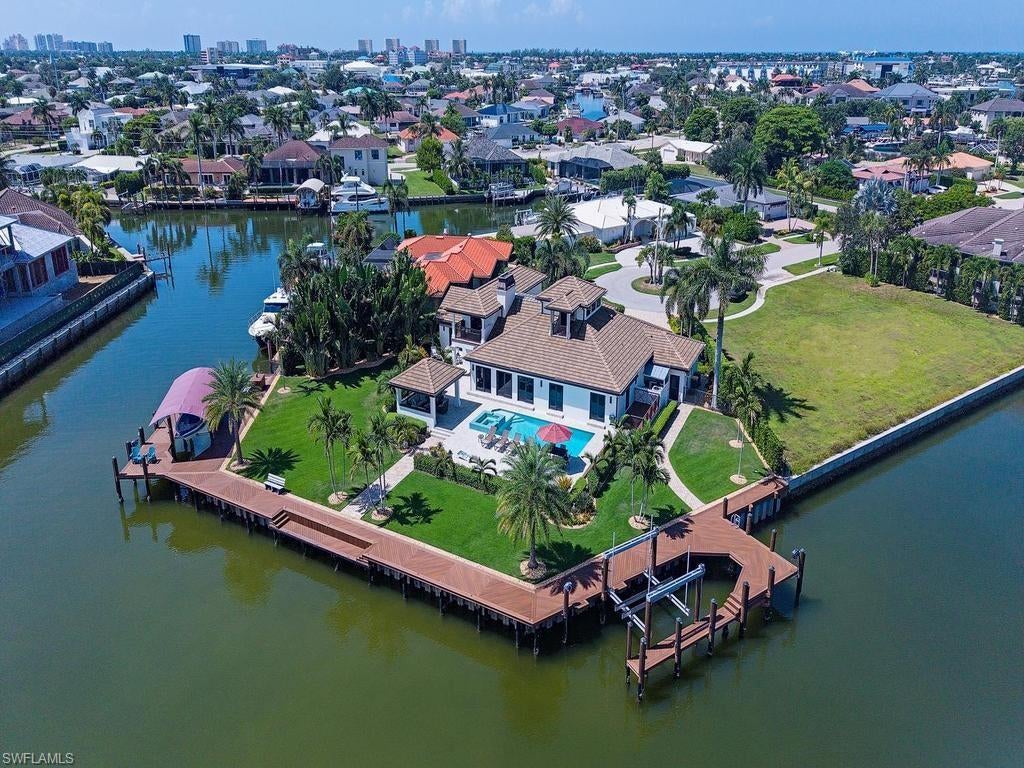 Welcome to 919 Sundrop Court, an exceptional waterfront residence on a rare tip lot in Marco Island, surrounded by water on three sides and featuring about 244 feet of seawall. Rebuilt in 2012, this beautifully updated home offers gracious living, extensive outdoor spaces, and extraordinary boating access.

This two-story residence includes four bedrooms and three-and-a-half baths, along with several versatile living areas. The lush tropical landscaping and well-maintained grounds provide a sense of privacy. Inside, you’ll find travertine stone flooring, warm hardwood floors upstairs, a crafted wood staircase, and remote-operated window treatments that add comfort and style.

The main floor features two-bedroom suites. The primary suite is a private retreat with a spa-like bath, a jetted tub, an oversized shower, and a spacious walk-in closet. Sliding glass doors lead to the outdoor living area, while an adjoining office offers a quiet workspace. The second bedroom has access to a sauna room for relaxation.

At the heart of the home is a stunning kitchen with Montoro countertops, Wolf appliances, Sub-Zero refrigeration, a wine cooler, Miele coffee station, and a water-filtration system. 

Upstairs, a spacious loft provides additional gathering space and panoramic views of Marco Island, including the Gulf of America and the Marco Island Bridge. Two more bedrooms and a shared bath complete this level, with one bedroom opening to a private balcony overlooking the pool and waterways.

The expansive outdoor area features a heated saltwater pool and spa, offering ample space for relaxation, dining, and entertaining. A gazebo and outdoor grill enhance the setting for enjoying Marco Island’s outdoor lifestyle, while automatic hurricane screens provide additional safety.

The home includes a 30 kW Kohler generator and separate tanks for both the pool heater and indoor fireplace. Boating enthusiasts will love the extensive dockage, accommodating a yacht of 100 feet or more, with a 20,000-lb boat lift and a 12,000-lb boat lift. Located just a minute from the Marco River, the property offers direct, no-bridge access to the Gulf of America.

Near the dock, you'll find a custom live well and multiple freshwater hoses, as well as an air-conditioned room suitable for boating gear, fitness, or additional storage. The garage features epoxy flooring and extensive cabinetry for functional storage.

919 Sundrop Court combines a rare tip-lot setting, water on three sides, exceptional dockage, and direct Gulf access, all within beautifully landscaped grounds. This thoughtfully designed home is perfect for both everyday living and entertaining, making it a unique waterfront opportunity on Marco Island. Experience the best of waterfront living in this exceptional residence.