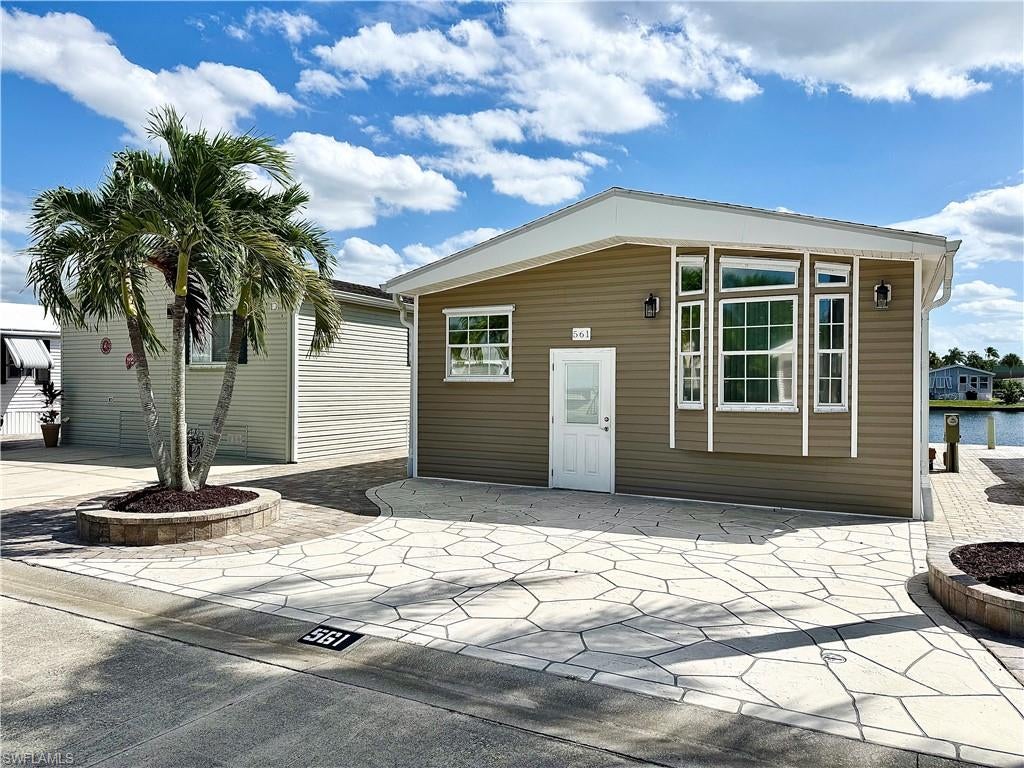 Situated on the water, this 1Br/2Ba home is affordable and a location where you OWN YOUR OWN LAND when you purchase your home in NAPLES, FLORIDA! It is positioned within Imperial Wilderness Condominium Association, a gated 55+ community that was never flooded! In 2025, new plank flooring was installed throughout the entire home. The refrigerator was replaced in 2023 and the A/C in 2022. This home boasts updated exterior features (roof, siding, pavers, sea wall, & mini yard — all in 2017 & 2018). The rear of the home faces south. Plus, you’ll appreciate the high ceilings and under-the-house storage space. On top of all of these attributes, the community is located approximately 3 miles to shopping and restaurants, 11 miles to the Naples beaches, and 8 miles to the Marco Island beaches. Airport access is also easily attainable— a 45-minute drive (RSW). Maximizing the opportunity to economically own property in Naples, FL, the HOA fee of $898. per quarter is exceptionally reasonable. That fee covers many of your needs: the advantage of a gated community, water, sewer, lawn care, basic cable, trash, recycling, and community amenities. Community amenities include 2 pools with spas, bocce, pickleball, pétanque, tennis, shuffleboard, billiards, ping pong, a library, clubhouse, 2 dog parks (1 pet, 40lb. max.), and a nature trail. Electric golf carts are allowed in this community, and there is an extremely active events calendar.