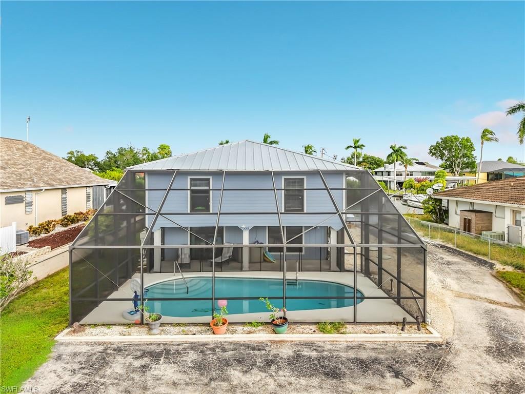 Seller is offering $15,000 in seller concessions. Set on a quiet private road in Bokeelia's Serenity Cove, this two-story waterfront pool home offers direct Gulf access with no bridges, putting Pine Island Sound, Charlotte Harbor, and the Gulf a short boat ride away. The dock includes a boat lift with canopy, and a shared boat ramp on the east side of the property makes launching easy. The screened, heated pool was recently resurfaced and sits at the front of the home next to a long covered patio. That layout leaves the canal side open for entertaining, with a shaded patio under the upper deck and a built-in brick grill near the water. The home has Hardie board siding, a metal roof installed in 2024, and impact windows. There is plenty of parking in front for trucks, trailers, and guests, and there is no HOA. Stairs lead up to a covered entry deck and the main living level, which has luxury vinyl plank flooring throughout the open kitchen, living, and dining areas. The kitchen features white shaker cabinets, butcher-block countertops, a stone mosaic backsplash, stainless steel appliances, and a large center island. A sliding glass door opens to a screened porch overlooking the canal. The primary suite is large and has a private bath. Two additional bedrooms share a full guest bath. The fully enclosed ground level has tile floors and beadboard wainscoting. It includes a large family room that opens to the pool area, an oversized butcher-block island with bar seating, a home gym, a game room, a full bath, and an unfinished workshop. Mini-split systems cool the ground level, and central AC serves the upstairs.