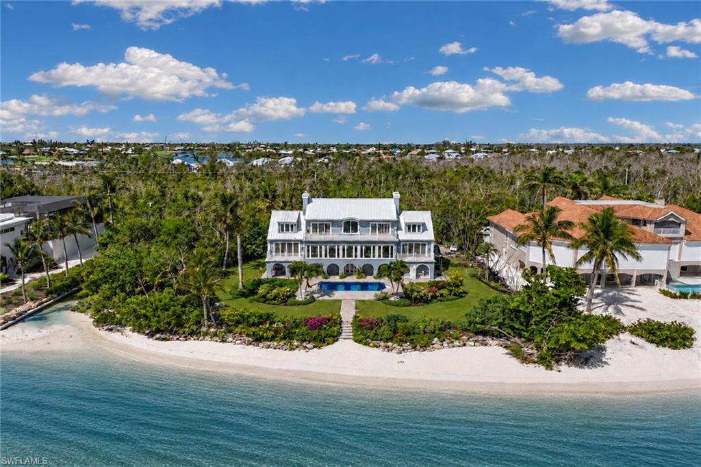 One or more photo(s) has been virtually staged, AI generated or rendered.  Experience the pinnacle of coastal living with this extraordinary 5,542-square-foot beachfront residence on Sanibel Island. Positioned on a private .86-acre lot adjoining protected conservation land and boasting 150 feet of waterfrontage. Designed for elegance and comfort, this four-bedroom estate captures sweeping bay views from nearly every room, the home features gracious living and dining areas with a fireplace and walls of glass that open to breathtaking panoramas. The expansive layout includes an inviting spacious kitchen with wide water views, a luxurious and spacious primary suite, a private office, and a serene sitting room to enjoy bay views, all accentuated by timeless hardwood flooring and impact-rated windows and doors. The top floor houses guest suites and a second primary suite. Gi outside to an inviting heated beachfront pool overlooking the wide bay, an ideal setting for tranquil relaxation or refined entertaining. With unmatched privacy, stunning natural surroundings and potential to create a private world-class single-family retreat, this property offers an exceptional opportunity to own one of Sanibel Island’s desired waterfront addresses. The home received damage to the lower non-living area during Hurricane Ian, the pool and garage have been restored, but storage areas, landscape and irrigation system requires repairs and updates. The home is in the sought-after area of Bird Lane within a few minutes of the Sanibel causeway and bridge for easy access on and off the island and offers incredible potential for updating and personal touches. The home is being offered in as-is condition. One or more photo(s) have been virtually staged, AI generated or rendered.