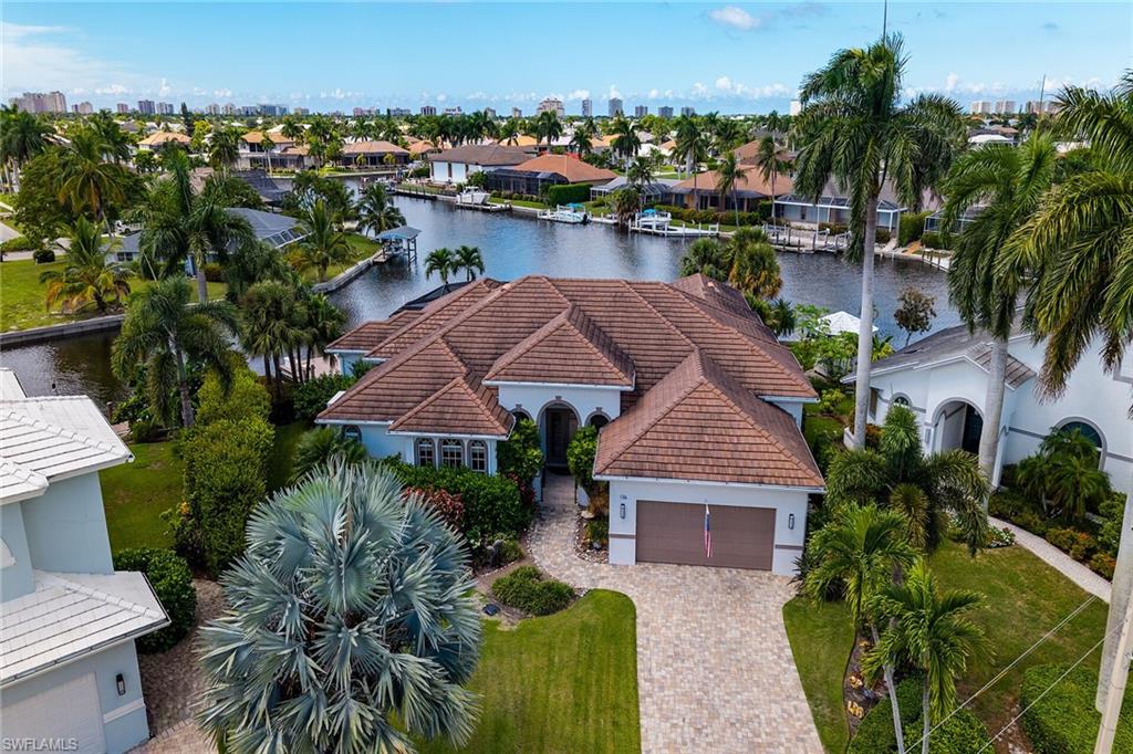 One or more photo(s) has been virtually staged, AI generated or rendered.  Superior quality expanded Divco model with over 3600 sq ft and terrific storage space throughout, offers a perfect blend of luxury, comfort, and coastal living.  Set on an oversized, over 1/3-acre lot with 146 ft of waterfront, sweeping wide converging waterway views and coveted SW exposure. A cook’s dream kitchen, equipped with all updated premium Jenn-Air and Thermador appliances, granite counters, a center island, and a large pantry. A spacious peninsula with seating for six seamlessly connects the kitchen to a circular breakfast nook and the family room, where custom entertainment center, cozy gas fireplace and enchanting water views create an inviting atmosphere. Entertainment flows effortlessly from the open living and dining areas through pocketing impact-glass sliders to the expansive upgraded panoramic screened lanai. Natural light, further enhanced by transom widows, fills the bright and airy living areas.  The outdoor space features a shimmering re-surfaced salt-water pool and spa, travertine pool deck, and upgraded granite wet bar with seating and cabinetry for outdoor entertaining.  Travertine paths lead to the fenced grassy yard, perfect for recreation, and the updated boat dock and new 13,000 lb Neptune boat lift (2018). The primary suite offers a tranquil retreat with stunning water views, rich wood floors, a sitting area, direct lanai access, dual custom walk-in closets, and luxurious ensuite bathroom.
The split bedroom plan with two guest bedrooms on opposite side from the primary bedroom offers privacy.   All 3 ½ bathrooms, including a pool bath, have been exquisitely appointed and remodeled by premier Marco Island contractor, Sea Coast Construction Services. Double leaded glass doors welcome you to the handsome office/den complete with built-ins, two desks, and bookshelves. Large separate air-conditioned exercise /hobby/flex room off the garage (non-confirming space) is complete with Porcelain tile floors, loads of cabinets, and an expansive upstairs loft for storage with fold up ladder and hoist for large items.  The oversized two-car garage features epoxy floors, storage closets, and even more loft storage space. Large Laundry Room with natural light boasts new Maytag HE jumbo washer & dryer with granite counters and loads of cabinet and closet storage space. Built for easy-living and peace of mind, this wonderful one-of-a kind residence includes a whole-house 32 kw Generac generator liquid air cooled quiet series (2022) with 500-gallon propane tank, house storm protections impact glass and automatic hurricane shutters, and updated security system with new front and rear cameras.  Additional enhancements in  include a modern tiled roof installed in 2018, extra wide paver driveway, Jandy Control System for pool heat and pump, newer water heater. Located on a quiet street, this coastal haven invites you to embrace an unparalleled waterfront lifestyle.