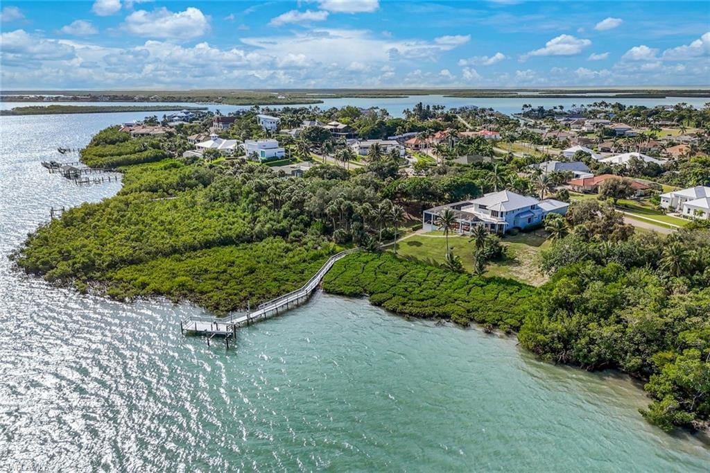 Experience the magic of sunrise over Barfield Bay, where coastal elegance meets island living. This exquisite custom home in the prestigious Marco Island Estates, is perfectly positioned on high elevation (no flood insurance required) and captures the essence of refined living with wide water views and luxurious upgrades throughout. Step inside and take in the stunning bay panorama that greets you from nearly every room. The open living area is bright and inviting, designed for both relaxed comfort and effortless entertaining. The newly remodeled kitchen is a dream for any cook, featuring quartz countertops, custom cabinetry, Sub-Zero refrigerator, Wolf cooktop, double ovens, a beverage and wine cooler, and even an extra ice maker for those perfect sunset cocktails. An elegant dining area sits just beyond, where family and guests can enjoy the views while dining in style. The first-floor primary suite has been completely transformed into a serene retreat, offering a generous sitting area, two walk-in custom closets, and a spa-like bath with a large walk-in shower, soaking tub, and double vanities. Also on the main level is a private guest suite with its own full bath—ideal for visitors or as a home office—along with a convenient half bath off the main living space. Upstairs, two additional guest suites each feature their own private baths, along with a loft that opens to a wraparound terrace—perfect for morning coffee or evening stargazing. Step outside to the expansive screened lanai and you’ll find a resort-style setting designed to make the most of Marco Island’s endless sunshine. A sparkling pool and spa are framed by an outdoor kitchen and a separate pool bath, creating a seamless flow between indoor and outdoor living. The home is equipped with electric hurricane shutters, including upstairs, with several windows replaced with impact glass and a hurricane-rated garage door for added peace of mind. Additional highlights include three zoned air-conditioning units, a brand new washer and dryer, new luxury flooring, updated lighting and fixtures, electric window shades, a newer roof (2018), whole house water softener and water filter at kitchen sink, new electric blinds upstairs, and beautifully updated landscaping with a brick paver driveway leading to an oversized two-car garage. Boaters will love the private dock with a lift that easily accommodates a 30-foot boat, plus two jet ski lifts, with only a short two-hour window at low tide where access is limited. There’s even a storage area beneath the pool deck, perfect for kayaks and paddleboards. Enjoy quick direct boating access to Caxambas Pass and the Gulf of Mexico from your backyard, and soak in the tranquil beauty of Barfield Bay each day. This is more than a home—it’s a lifestyle of sunrises, open water, and pure island serenity. And for the ultimate in privacy, the adjoining lot is also available for purchase.