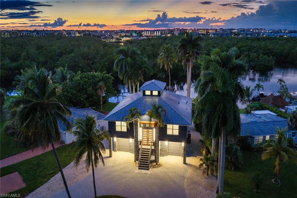 Welcome to this completely renovated waterfront residence, ideally minutes from Naples Bay, Bayfront, Fifth Avenue South and the best of Old Naples. Offering approximately 54 feet of seawall frontage, a new boat dock and protected western water and mangrove views toward Naples Bay, this exceptional home combines boating convenience, natural beauty and downtown accessibility, without HOA restrictions. The upper-level primary living space features an open-concept great room with custom wood ceiling detail, a spacious dining area, a powder bath and a chef's kitchen with a 48-inch gas range, a 54-inch side-by-side refrigerator/freezer, an oversized L-shaped island and abundant storage. Three bedrooms, each with a private ensuite bath, complete the upper level. The lower level is ideal for guests or extended family, offering a secondary living area, a private ensuite bedroom and a kitchenette with a microwave and under-counter wine refrigerator. Two expansive rear decks capture unobstructed water, mangrove and western sunset views. Additional highlights include impact-resistant windows and doors, neutral wood flooring, custom tilework, a circular driveway and ample garage storage.