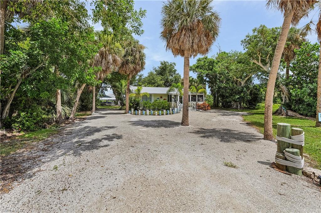 Welcome to this incredibly charming turn key furnished waterfront cottage paradise! Tucked beneath sprawling oaks, mature mahoganies and swaying palms, this secluded St. James City retreat offers nearly half an acre of shaded, private waterfront bliss — yet it's just minutes from some of the island's favorite restaurants, bars, and local hangouts. And did we mention the privacy? The property feels like your own tropical hideaway. Watch manatees and dolphins cruise the canal from your backyard, cast a line, or grill the catch of the day after bringing it in from your own 30-foot dock. Not fishing today? Two nearby fresh seafood markets make it easy to bring home the day's local catch. And if outdoor living is your thing, Enjoy mornings on your two screened porches — one overlooking the expansive backyard and waterfront, and another facing the large front yard. Morning coffee, afternoon cocktails, or a quiet evening outdoors — you've got the perfect spot for every mood. Inside, the cottage has been updated while keeping its unmistakable Old Florida beach-house character. The large butcher block kitchen island provides plenty of room for friends and family to gather for drinks, dinner, and fish stories, while the spacious living area keeps everything comfortable and inviting. One of the home's most memorable features is beneath your feet: unique hand-painted wood floors running throughout the cottage. Creative, colorful, and easy to maintain, they're almost guaranteed to become a conversation piece the moment guests walk through the door. The oversized primary bedroom offers a built-in vanity and two large closets, while the second bedroom has a generous closet of its own. The bathroom features a roomy walk-in tile shower, tile flooring, and a corner linen cabinet with deep shelving. The updated laundry room includes a newer front-loading washer and dryer, a new water heater, a generous butcher block folding counter, and upper cabinetry. When you're ready to explore, simply walk out to your dock, step aboard the boat, and go. From your backyard, it's approximately a fifteen-minute canal ride through beautiful mangroves, with incredible fishing, bird watching, and Southwest Florida nature along the way. Continue into Pine Island Sound, and a whole new world opens up — Sanibel, Fort Myers Beach, gulf waters, waterfront restaurants, and countless places to explore by boat. Or don't go anywhere at all. Fire up the grill, grab a cold drink, and enjoy the shade beneath the trees while boats, dolphins, and manatees pass by. This is exactly the Pine Island lifestyle people come for.