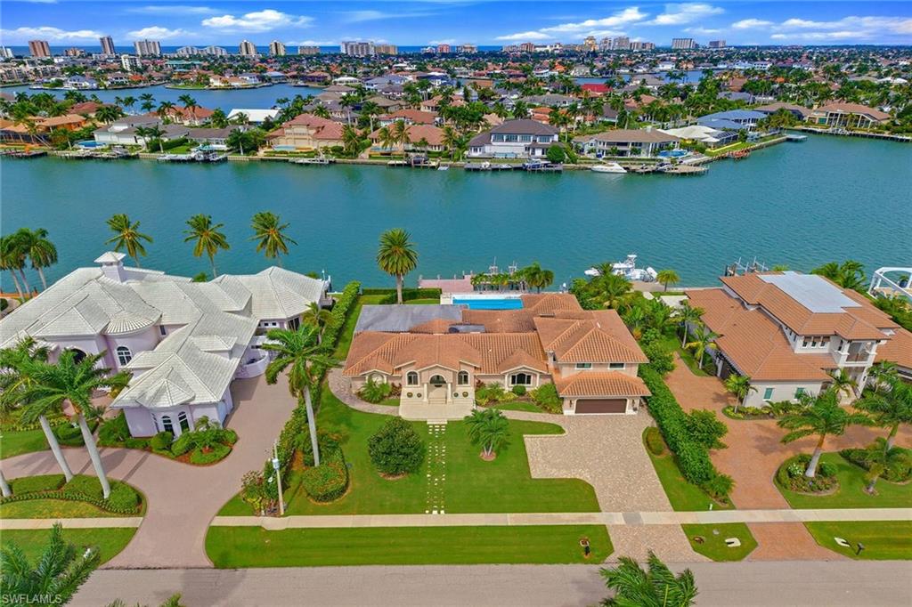 Don’t miss this exceptional opportunity in the prestigious Estate section on Marco Island as there are few prime waterfront locations left available. On a nicely elevated, beautifully landscaped half-acre lot along a protected extension of Roberts Bay, this five-bedroom, five-and-one-half-bath residence with den offers 125 feet of direct access frontage, western exposure, expansive waterway views stretching toward the city skyline and incredible sunsets. The deepwater setting provides quick, natural access from Smokehouse Creek to the 10,000 Islands and Gulf of Mexico, making this an ideal location for boating, fishing, shelling, sightseeing and exploring. The private dock features two slips with lifts and offers the ability to accommodate multiple boats/large yacht. While the residence has been remodeled since its original construction, the property offers tremendous potential for further transformation or could serve as the ideal setting to create a new dream home in one of Marco Island’s desired waterfront locations. The exceptional outdoor living spaces are the heart of the property. A spacious covered lanai features an outdoor kitchen and bar with abundant seating complemented by an additional covered patio. The approximately 16-by-50-foot pool includes a built-in table and spa, while waterside shuffleboard and expansive entertainment areas invite you to fully embrace the hallmarks of the Marco Island lifestyle, all framed by panoramic waterfront views and unforgettable sunsets. Adding to the versatility of the home is a private two-bedroom guest quarters on the second floor. Complete with a kitchenette and private patio, the area can be accessed through the main residence or via its separate entrance, providing flexibility for guests, extended family or additional living space. An oversized, air-conditioned three-car garage and workshop offers incredible space for multiple vehicles, storage and hobbies, including a soundproof room. Whether you are a car enthusiast, crafter, contractor or handyman, this unique space offers possibilities rarely found in a waterfront residence. This stands out as an amazing opportunity to create something special on Marco Island. Property to be sold as-is with the right to inspect.