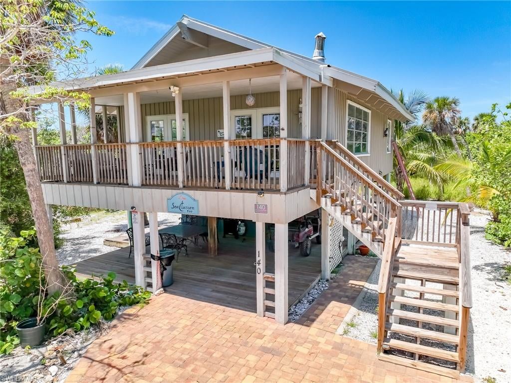 Authentic Old Florida Island Charm and timeless appeal combine in this beautiful 2-bedroom cottage, offering classic character with thoughtful updates, including a new metal roof installed in 2023. Inside, soaring cathedral tongue-and-groove ceilings, oak floors, and rich pecky cypress walls create a warm and inviting atmosphere. The open-concept layout was ahead of its time, featuring a spacious kitchen with a wraparound dining bar that flows into the living and dining areas. All living spaces open to an oversized covered front porch, perfect for relaxed outdoor living. The primary suite features glowing wood finishes and an en-suite bathroom with a tub/shower combination. The second bedroom offers dual closets and a cozy nook for more storage or decor, making it ideal for accommodating guests with comfort and style. Below the house, a shady wood deck offers a great space for grilling and entertaining. An adjacent enclosed room houses a full laundry area and extra storage. The landscaped front yard features native plantings and a curving paver driveway. This home enjoys a prime location close to the ferry landing, just a short golf cart ride to both the Gulf's sandy shoreline and the bayside beaches along Pine Island Sound. Boating, fishing, shelling, and island exploration are all easily accessible from this quiet, scenic spot. This charming cottage offers the best of island living—historic style, modern comforts, and one of the best floor plans of a house this size on the island...  all in a setting that captures the magic of North Captiva.   Whether you're seeking a peaceful getaway, a year-round retreat, or a vacation rental to offset costs while you enjoy the island lifestyle, this is a rare opportunity to own a genuine piece of North Captiva's heritage.